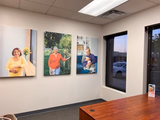 Interior reception area with three large portrait canvases on the wall beside a wooden desk