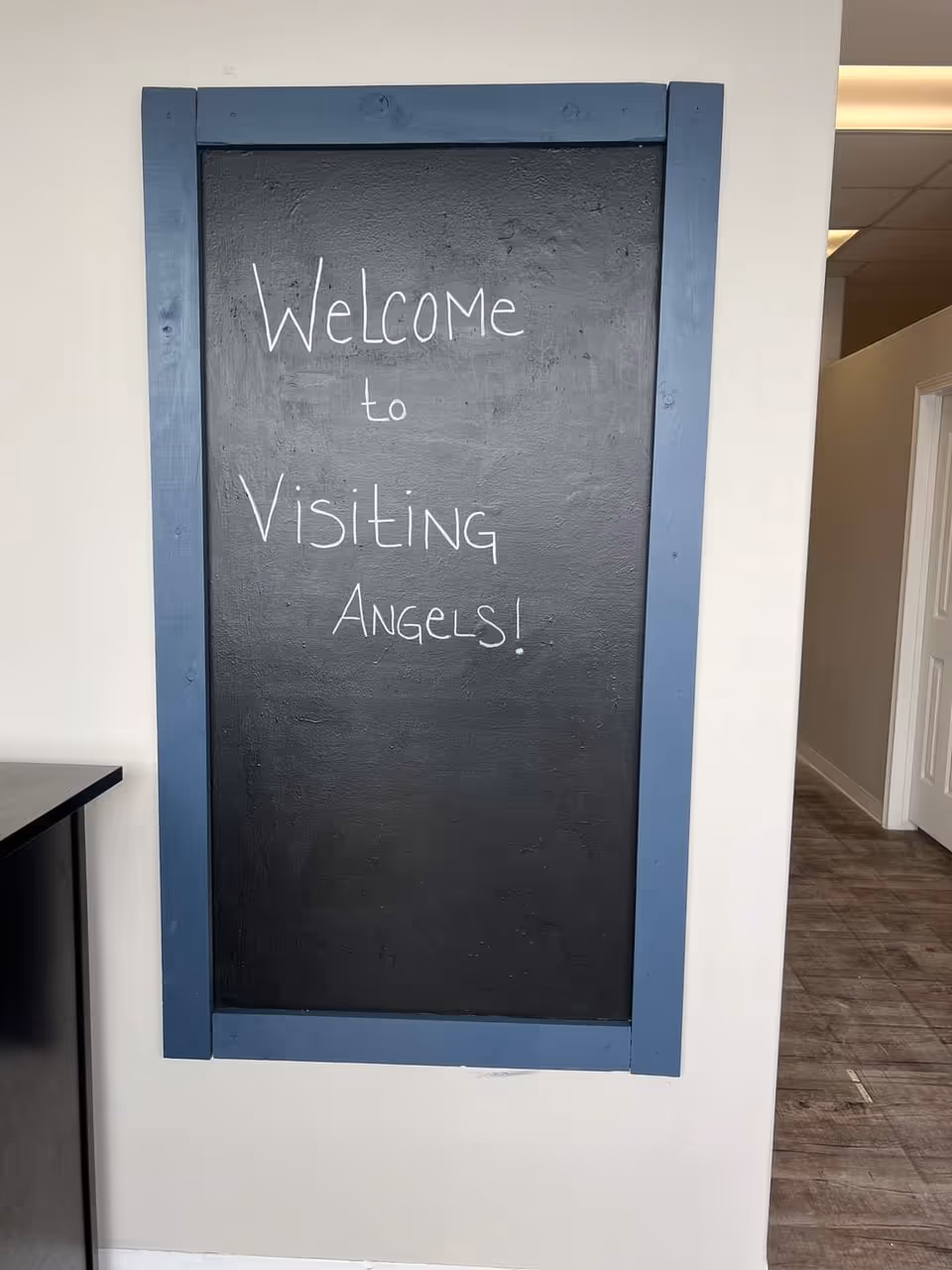 Interior hallway with a blue-framed chalkboard sign reading Welcome to Visiting Angels.