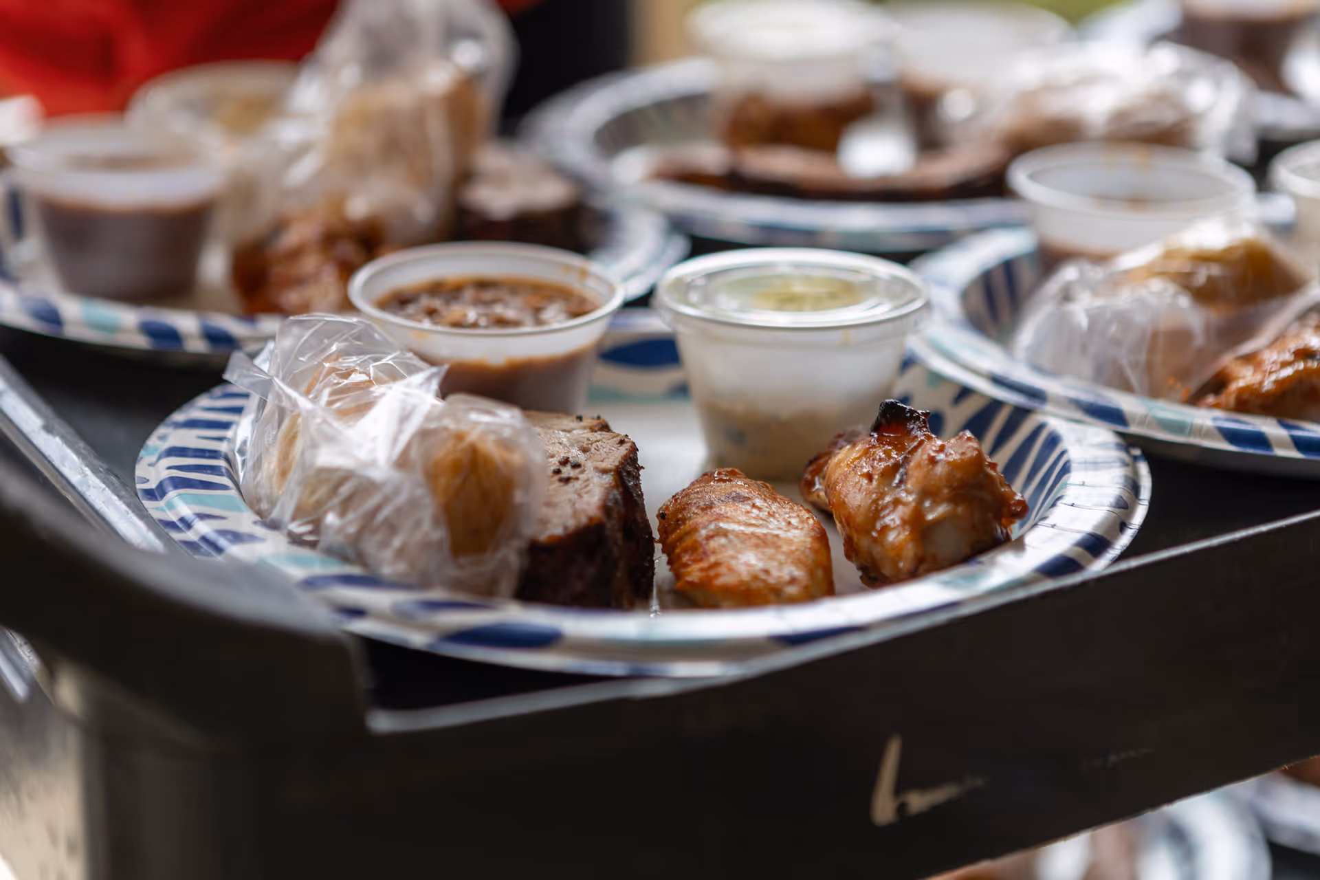 Close-up of disposable plates with assorted meals on a serving cart in a dining area.
