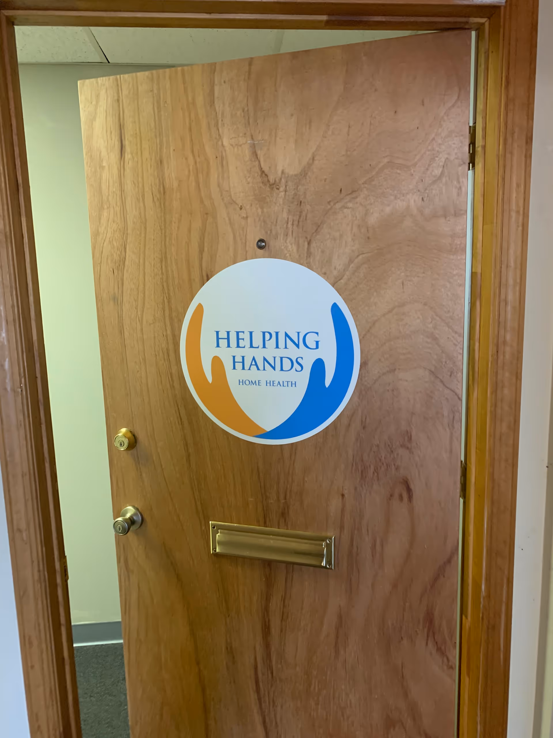 Wooden interior door with a circular Helping Hands Home Health sign.
