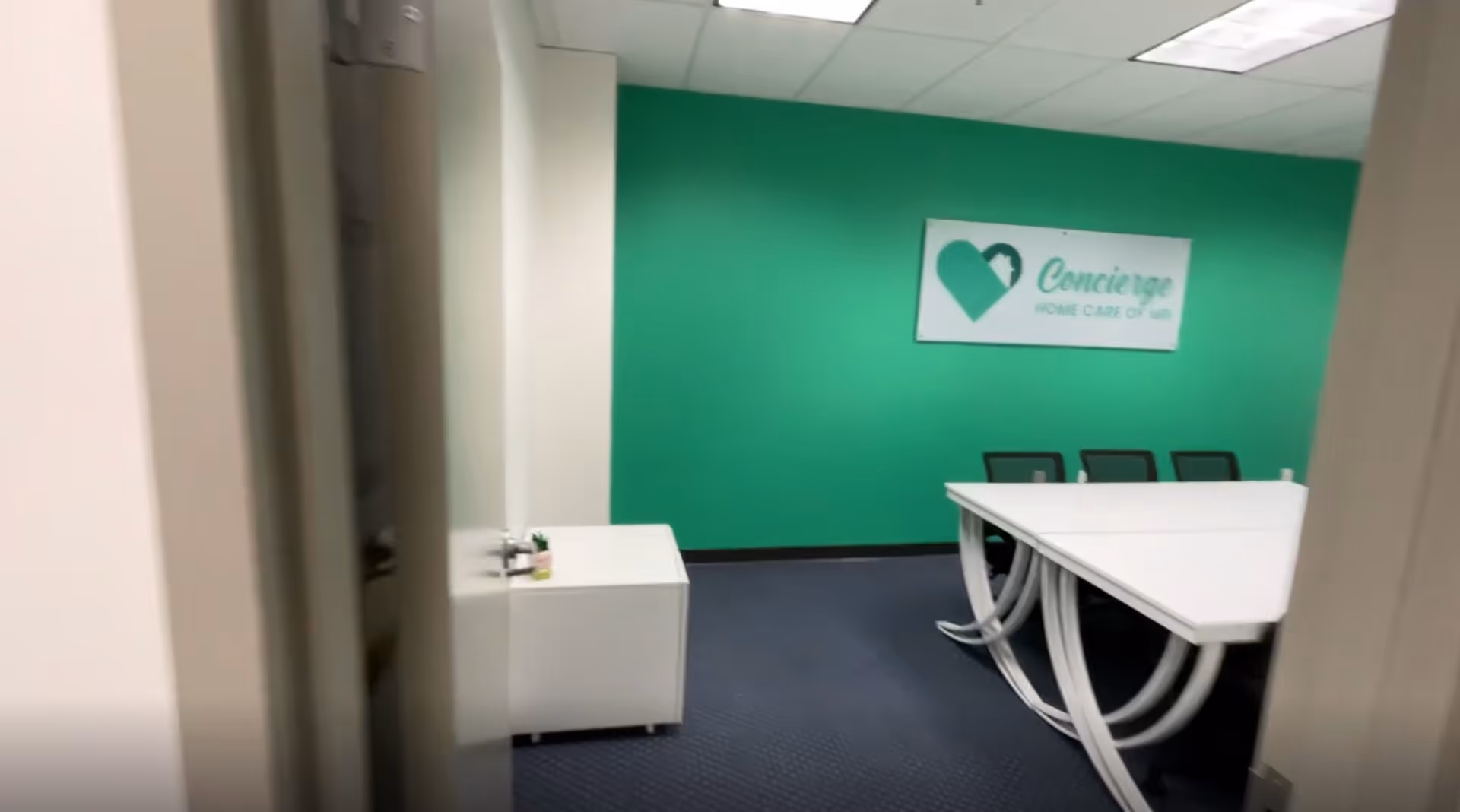 Interior conference room with a green wall, long white table, and chairs.