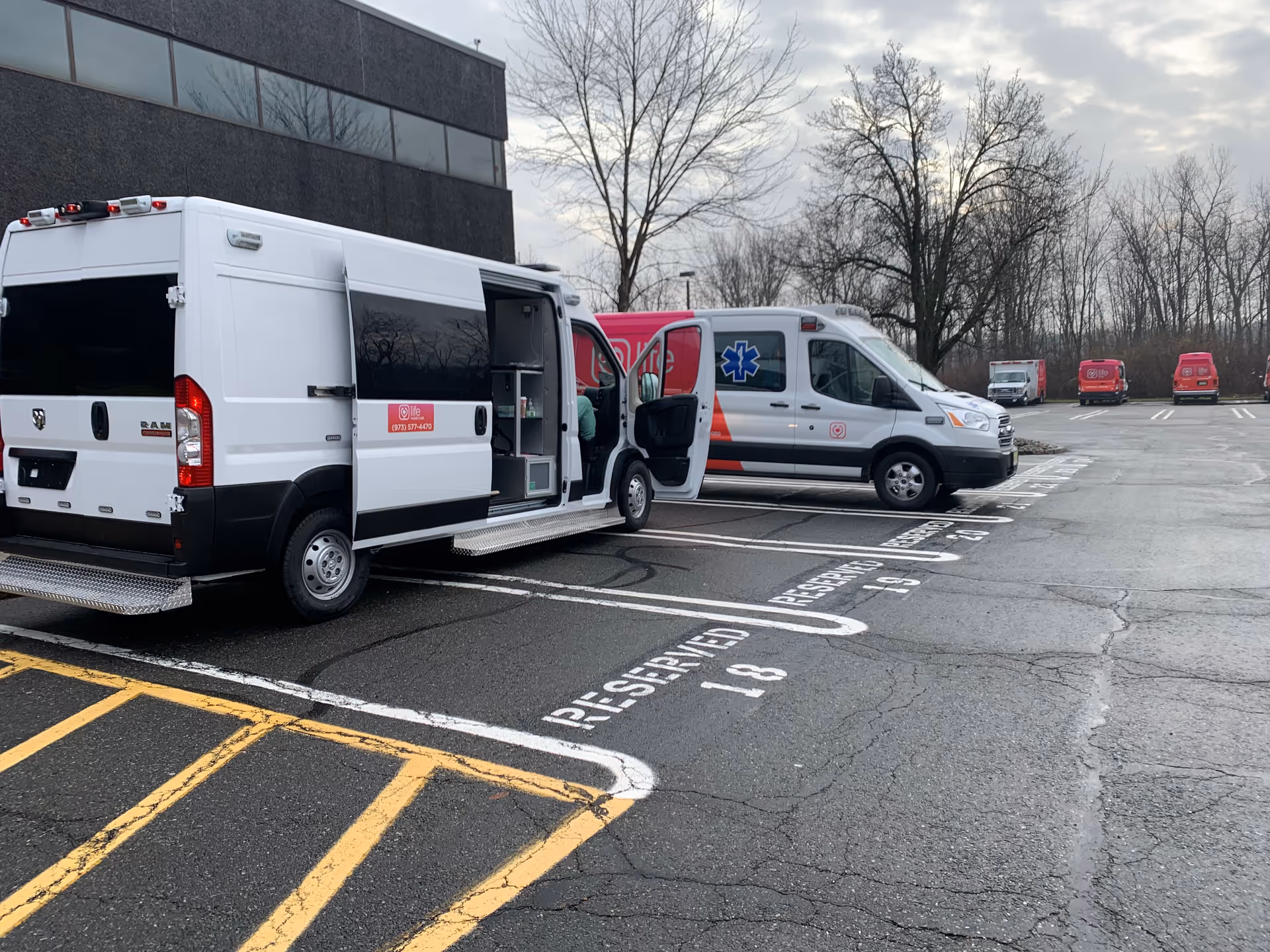Parking lot with white ambulances and a Life Medical vehicle beside a building
