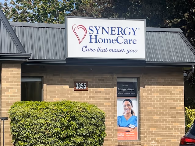 Exterior view of Synergy HomeCare facility with sign, brick walls, and shrub
