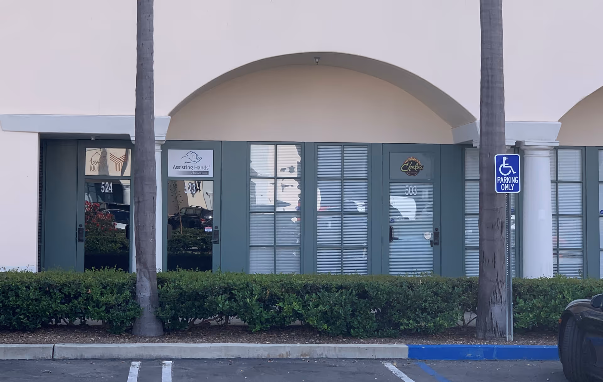 Exterior view of a storefront entrance with Assisting Hands Dana Point signage and handicap parking
