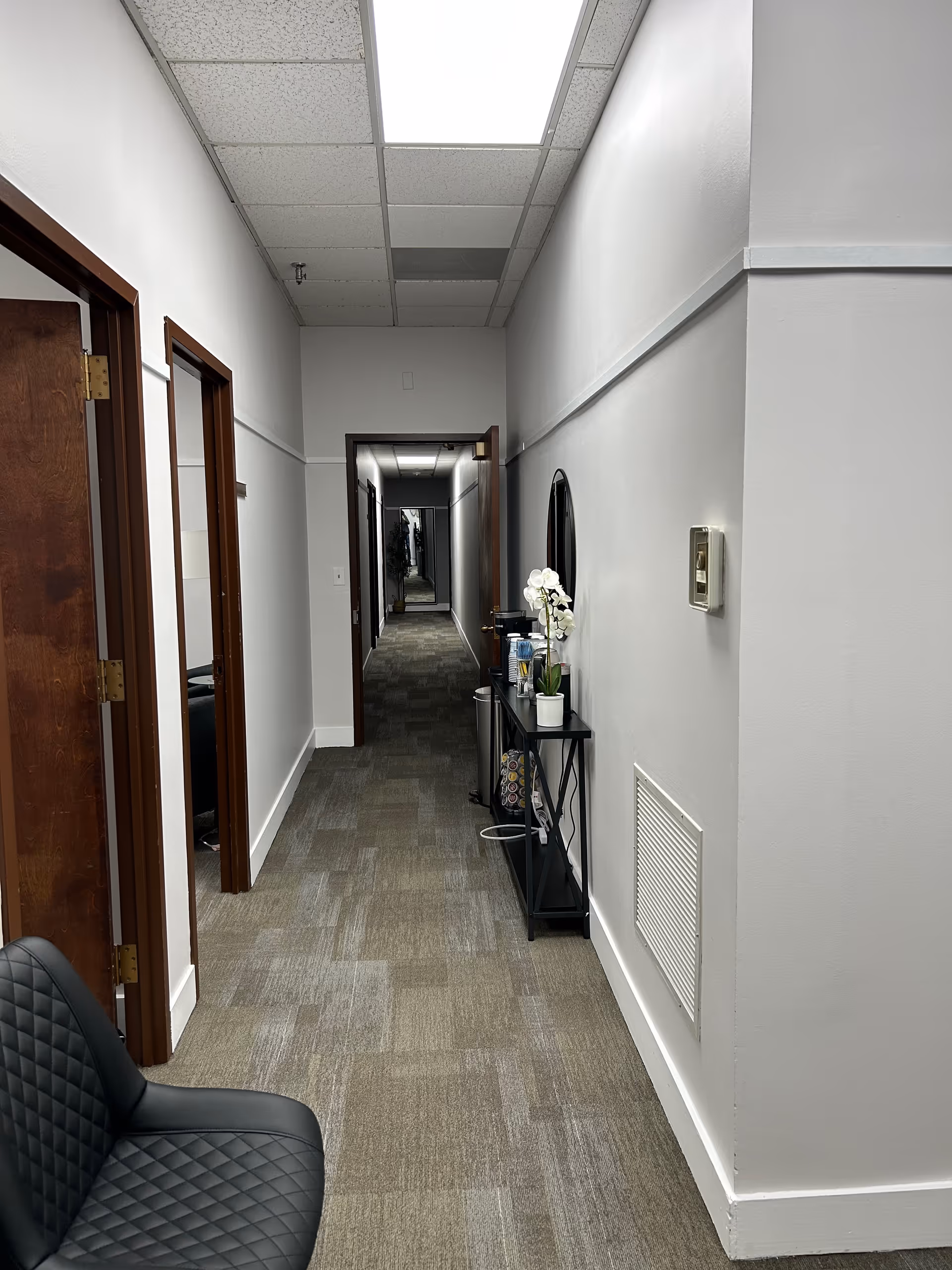 Long hallway in a senior living facility with doors and a console table.