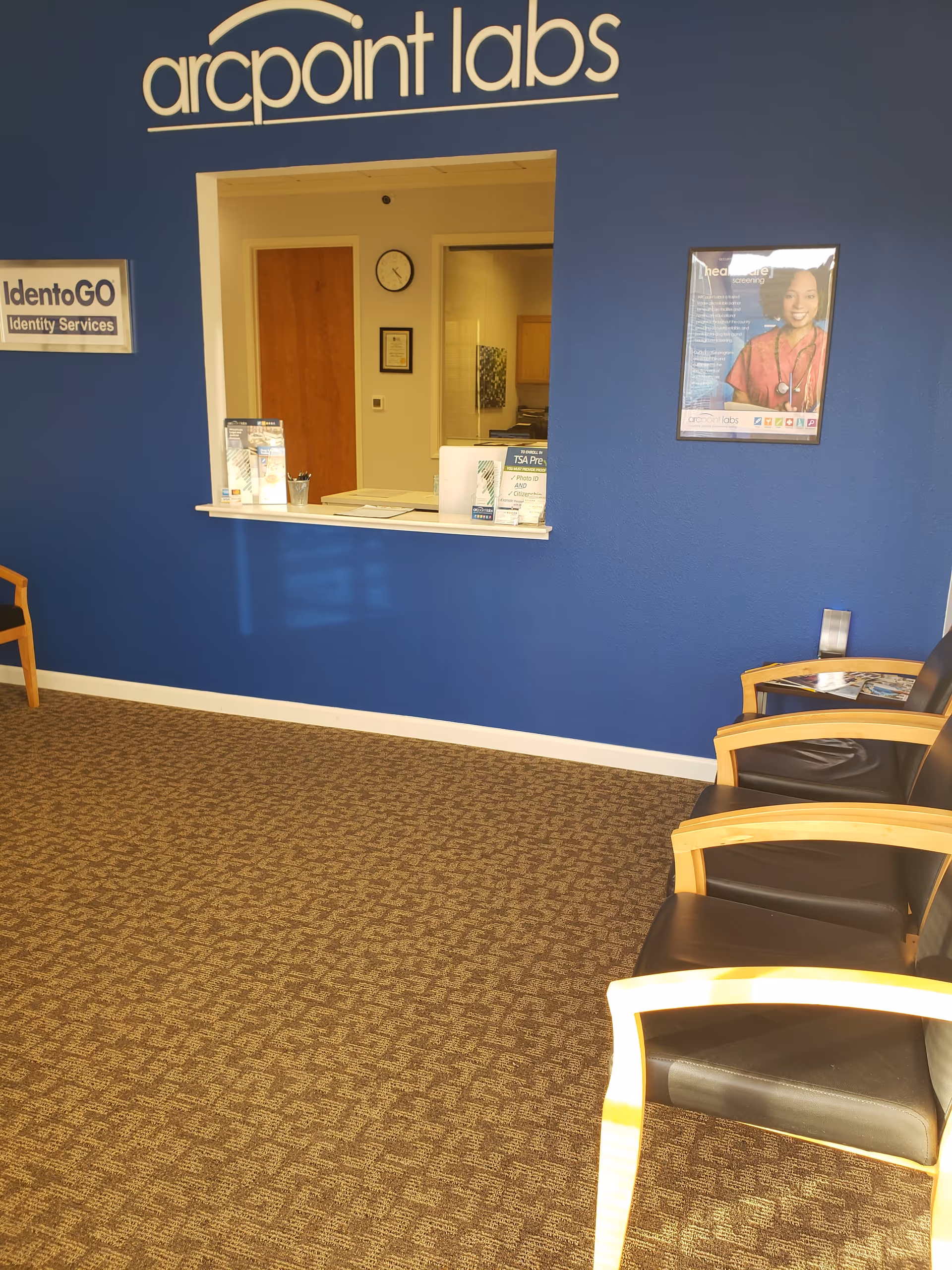 Blue wall reception area with seating and a service window at ARCpoint Labs.