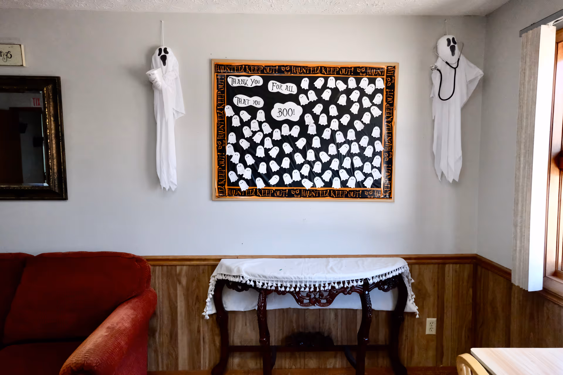 Halloween ghost decor on living room wall with table and couch