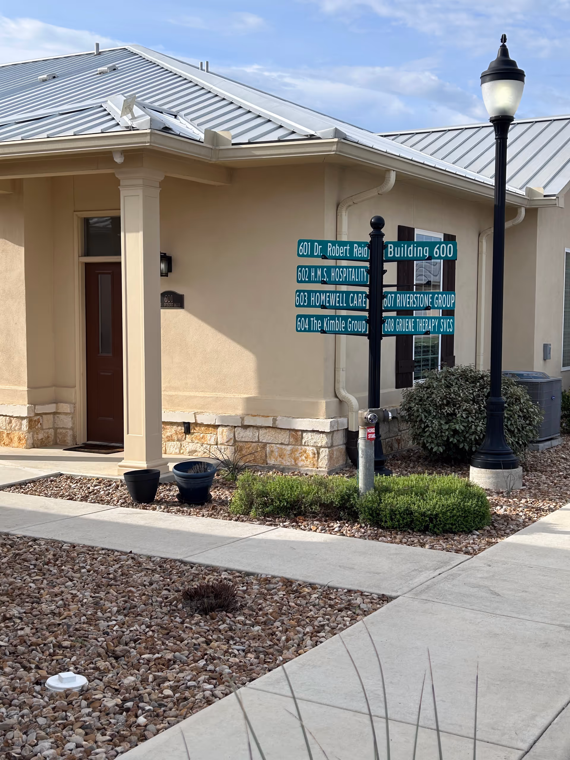 Exterior view of a HomeWell Care Services building with a signpost near the entrance.