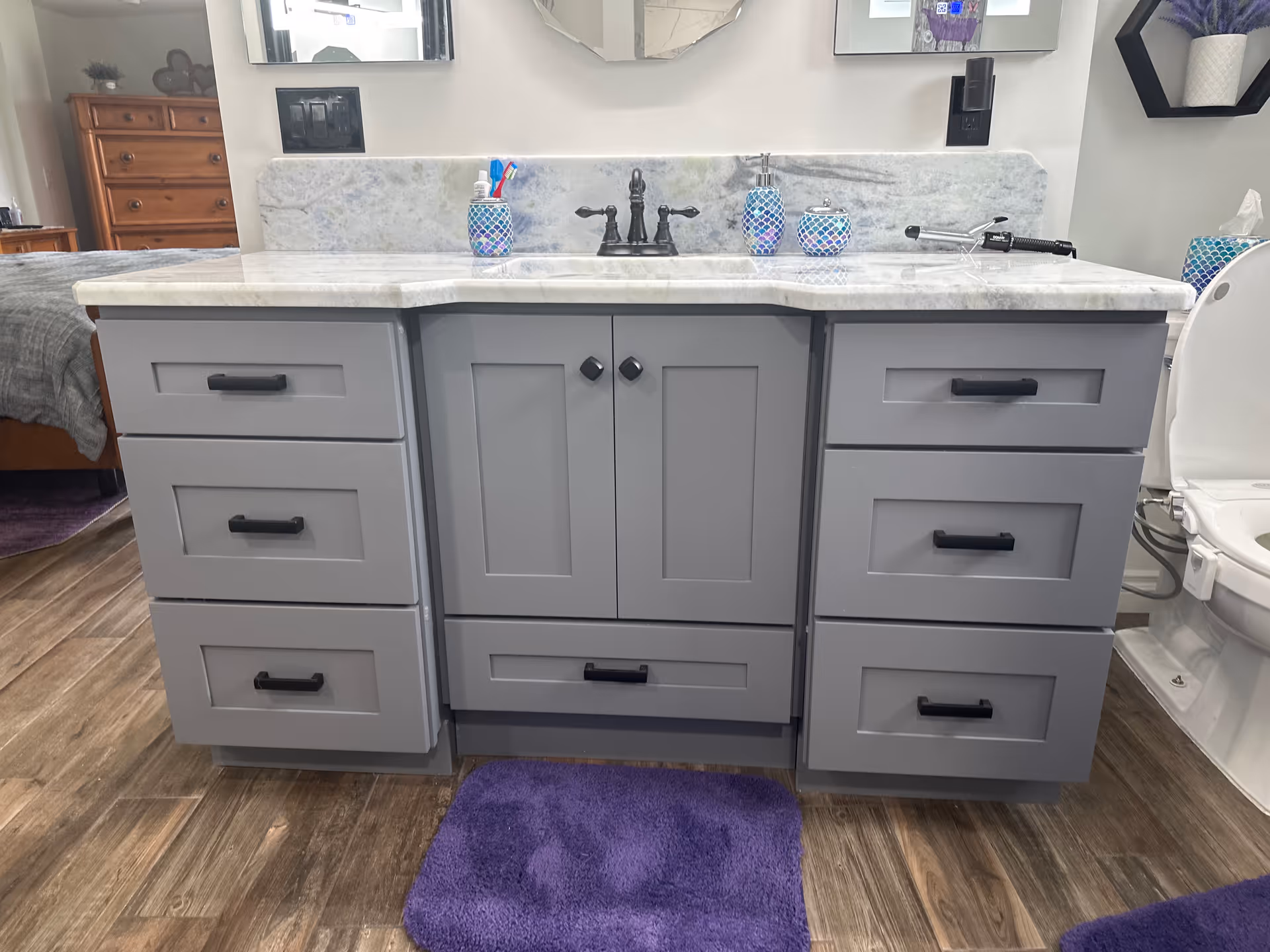 Grey bathroom vanity with marble countertop and sink in a senior living facility.