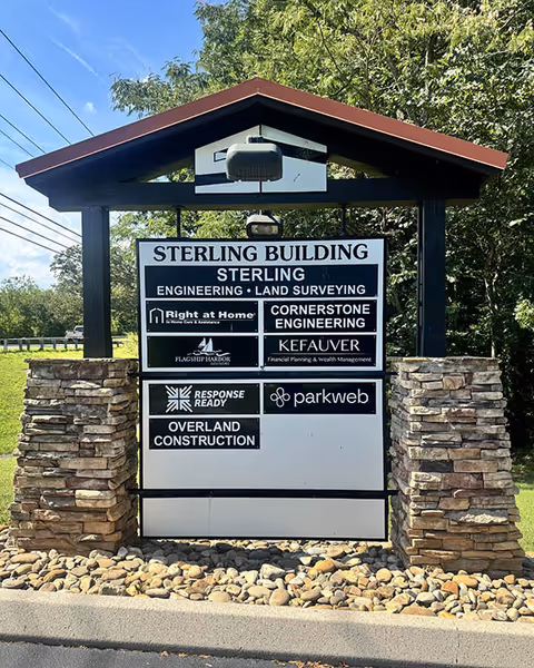Exterior sign for Sterling Building displaying Right at Home among logos.