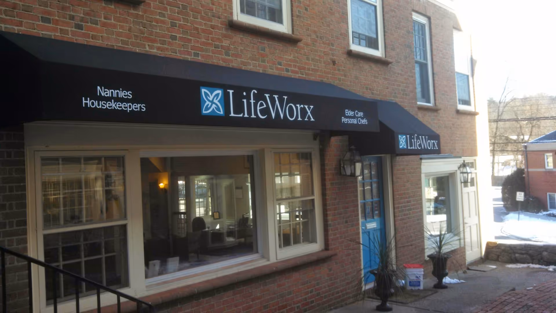 Brick building storefront with LifeWorx sign, blue door, and large front windows.