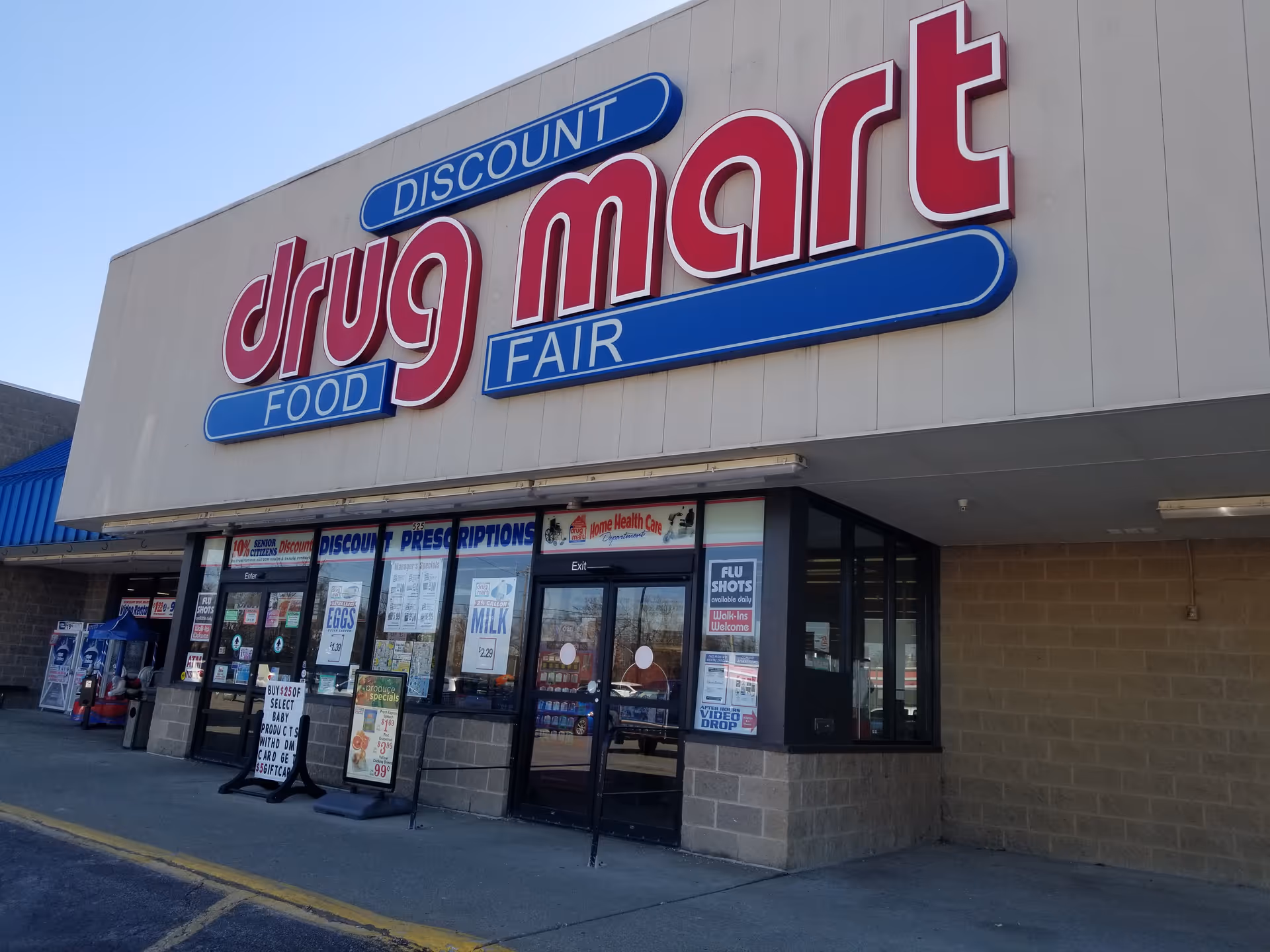 Exterior of Discount Drug Mart storefront with large red sign and glass entry doors.