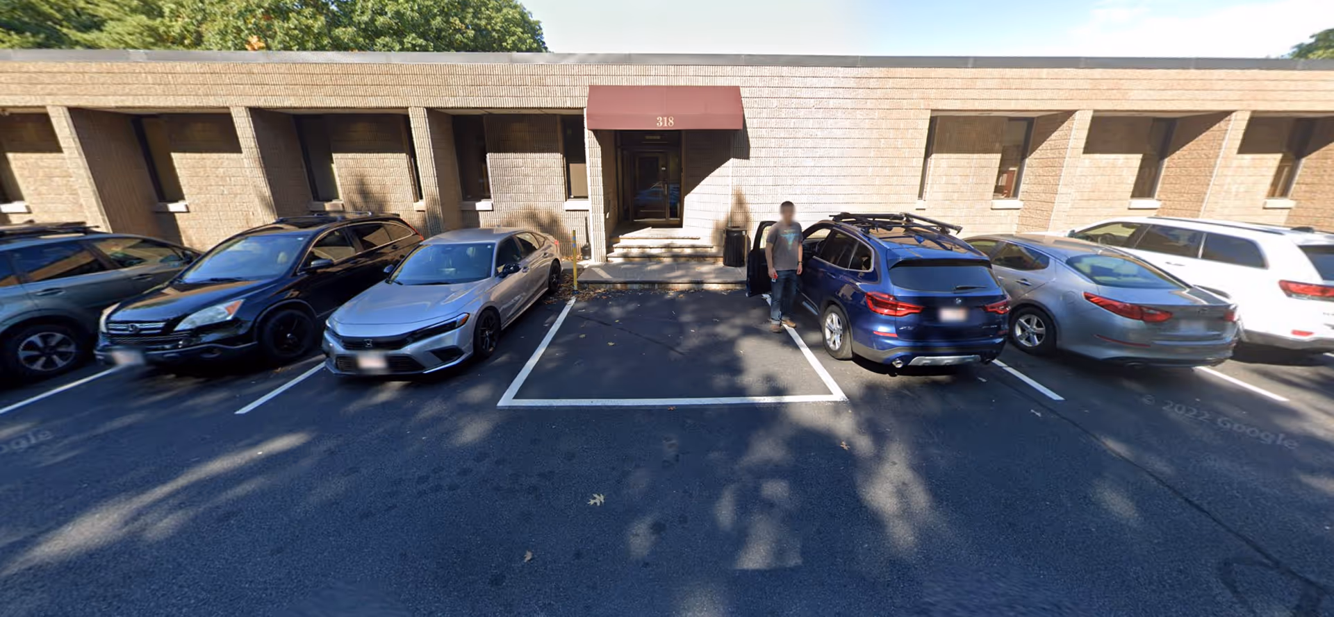 Exterior view of BrightStar Care facility with parked cars and a person near the entrance.