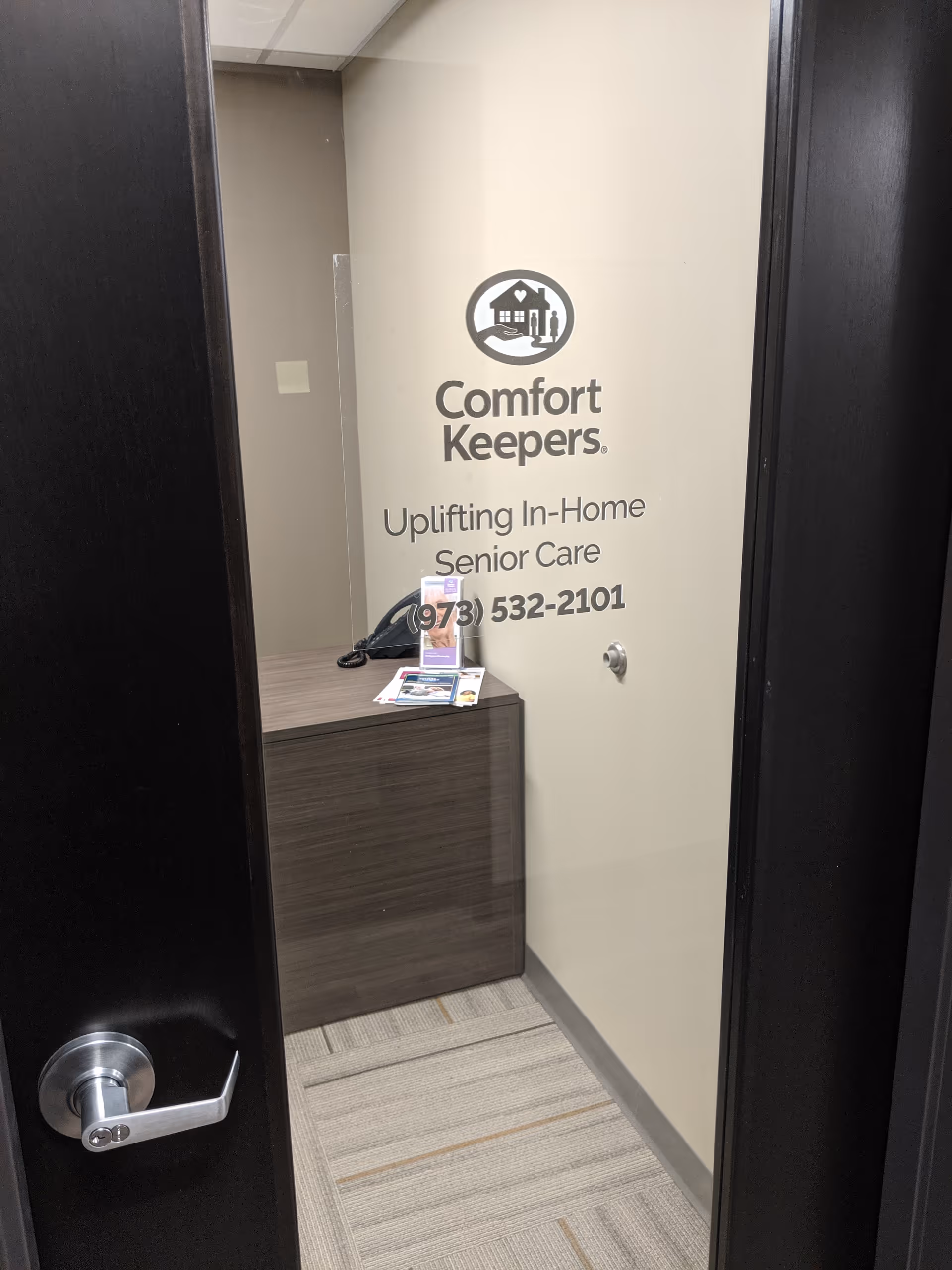 Open doorway reveals a reception desk with Comfort Keepers logo and signage.
