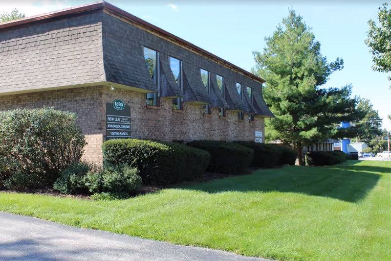 Exterior view of a brick senior home with a sloped roof and green lawn.
