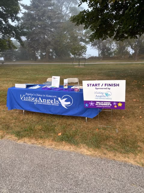 Outdoor park setup with a Visiting Angels bannered table for a start/finish event.