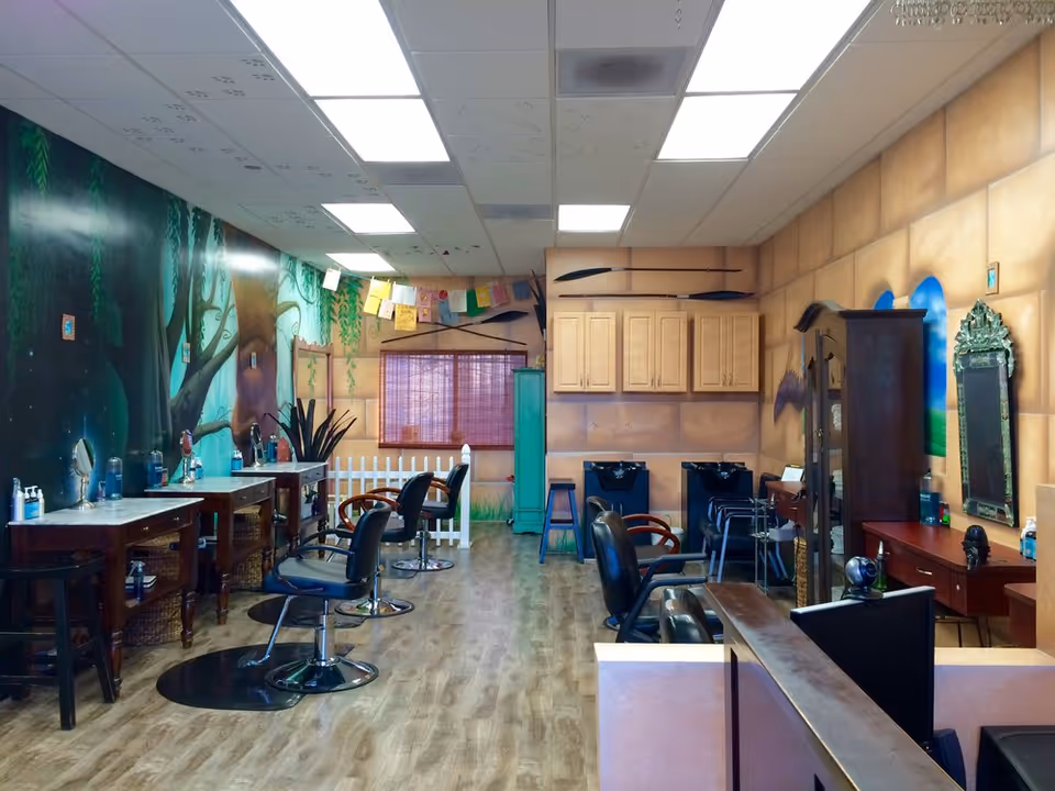 Hair salon interior with styling chairs, mirrors, sinks, and wooden cabinets.