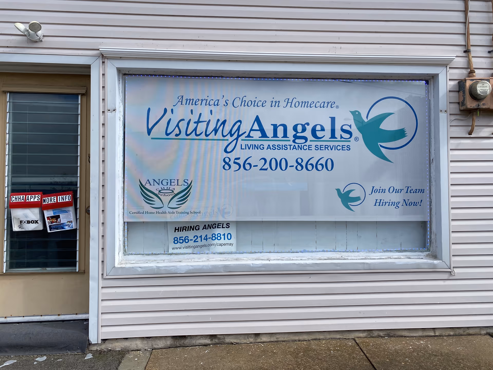 Exterior storefront with a large Visiting Angels sign displayed in a window.
