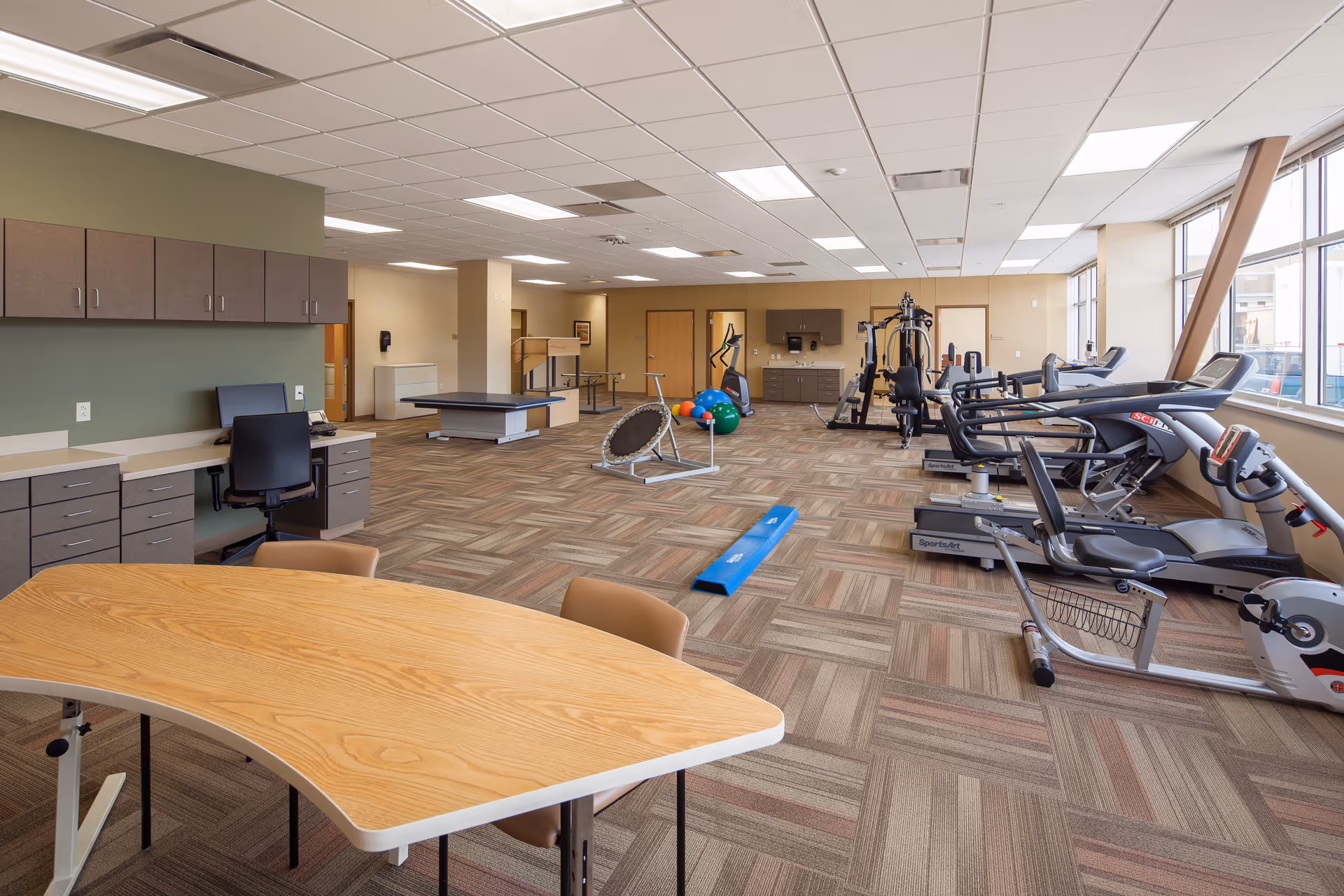 Interior fitness area with treadmills, weights, a trampoline, and a table in Drew Memorial Health System.