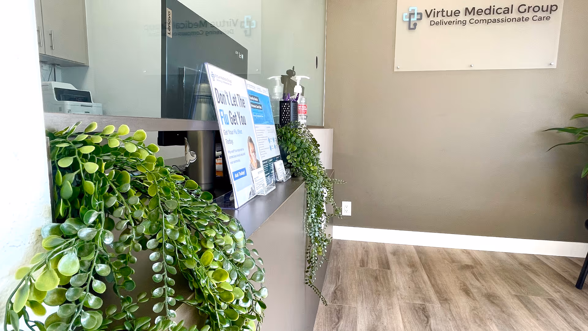Reception area with a counter, potted plants, and a Virtue Medical Group sign.