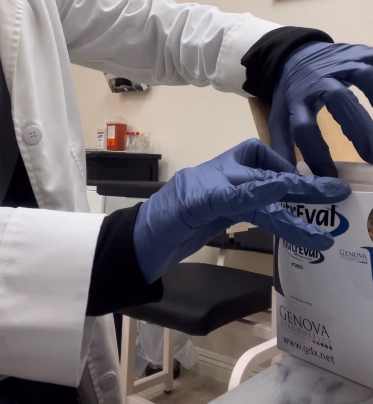 A clinician with gloves handles lab supplies during a phlebotomy procedure.