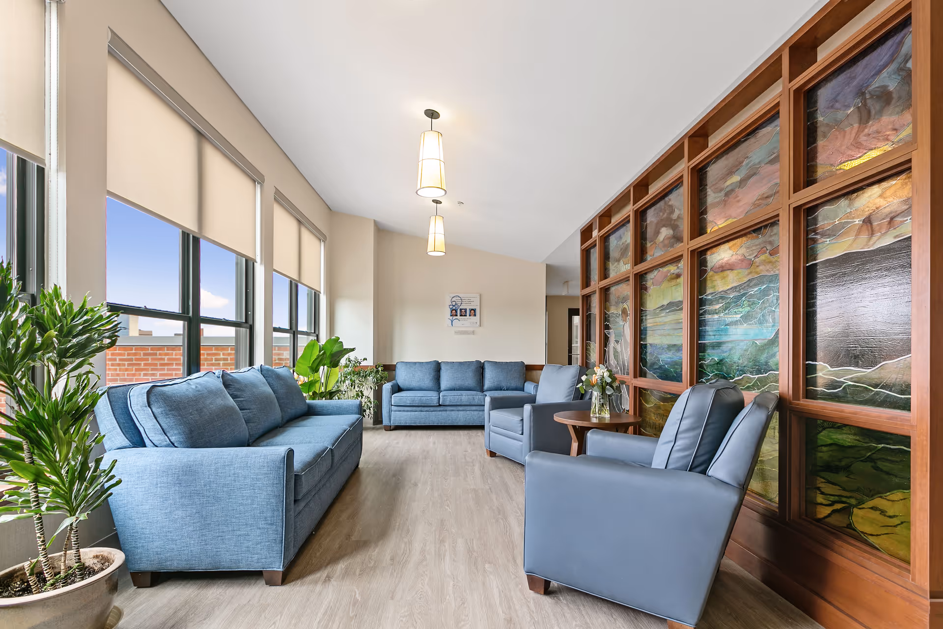 Bright lounge area with blue seating, plants, and a colorful wooden wall panel.
