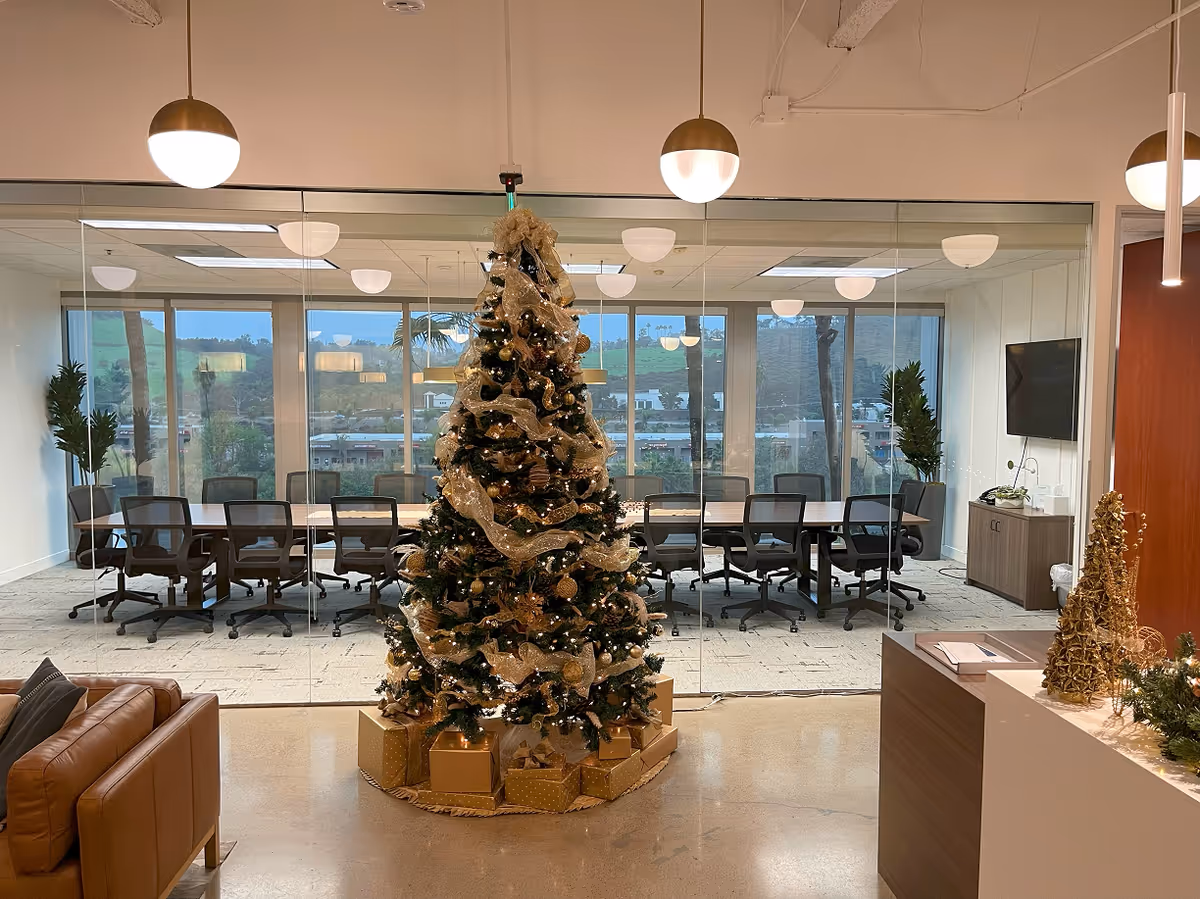 Modern conference room inside Caremarque with glass partition, Christmas tree, and wrapped gifts.