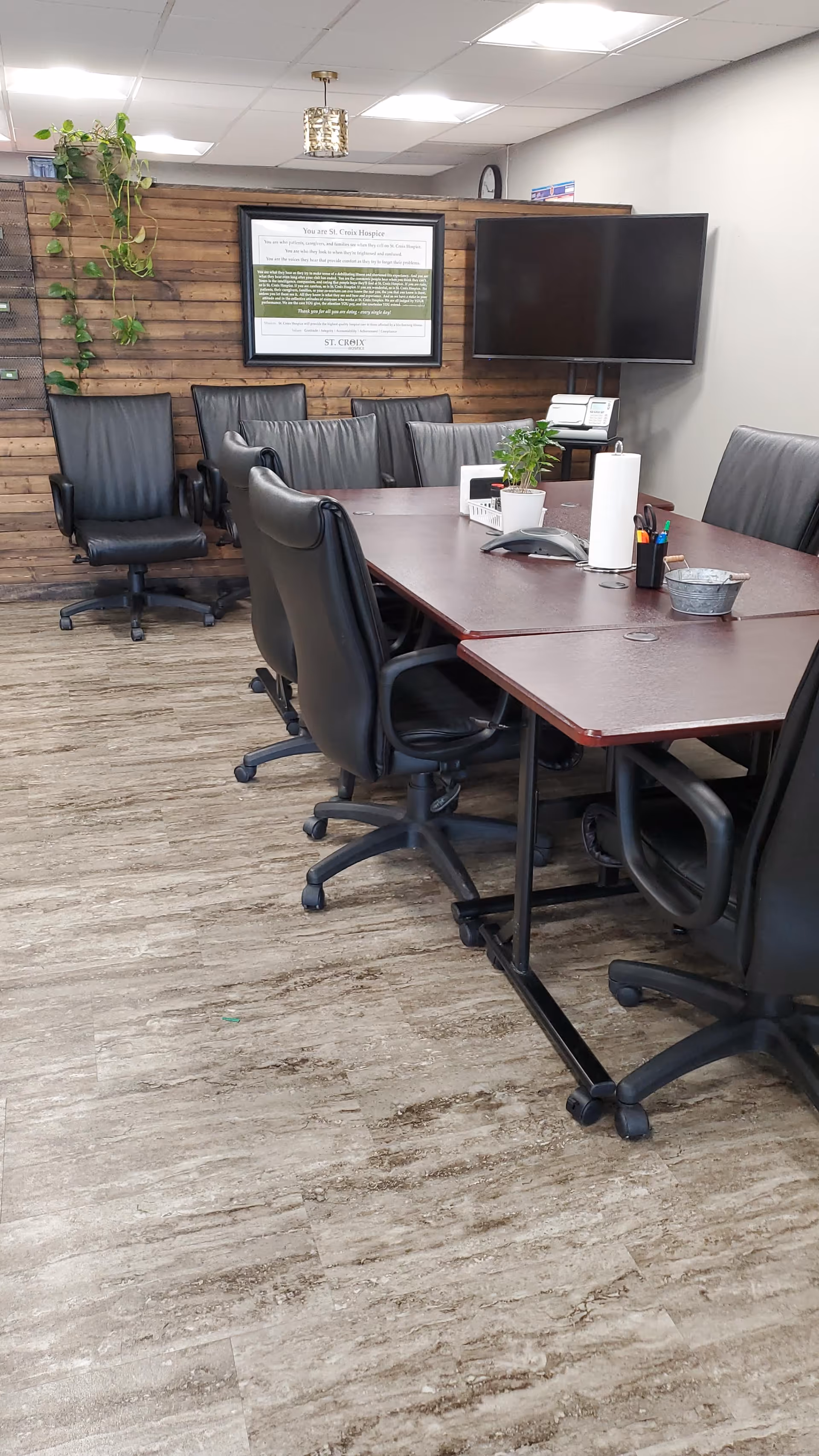 A modern conference room with a long table, black chairs, and wall-mounted TV.