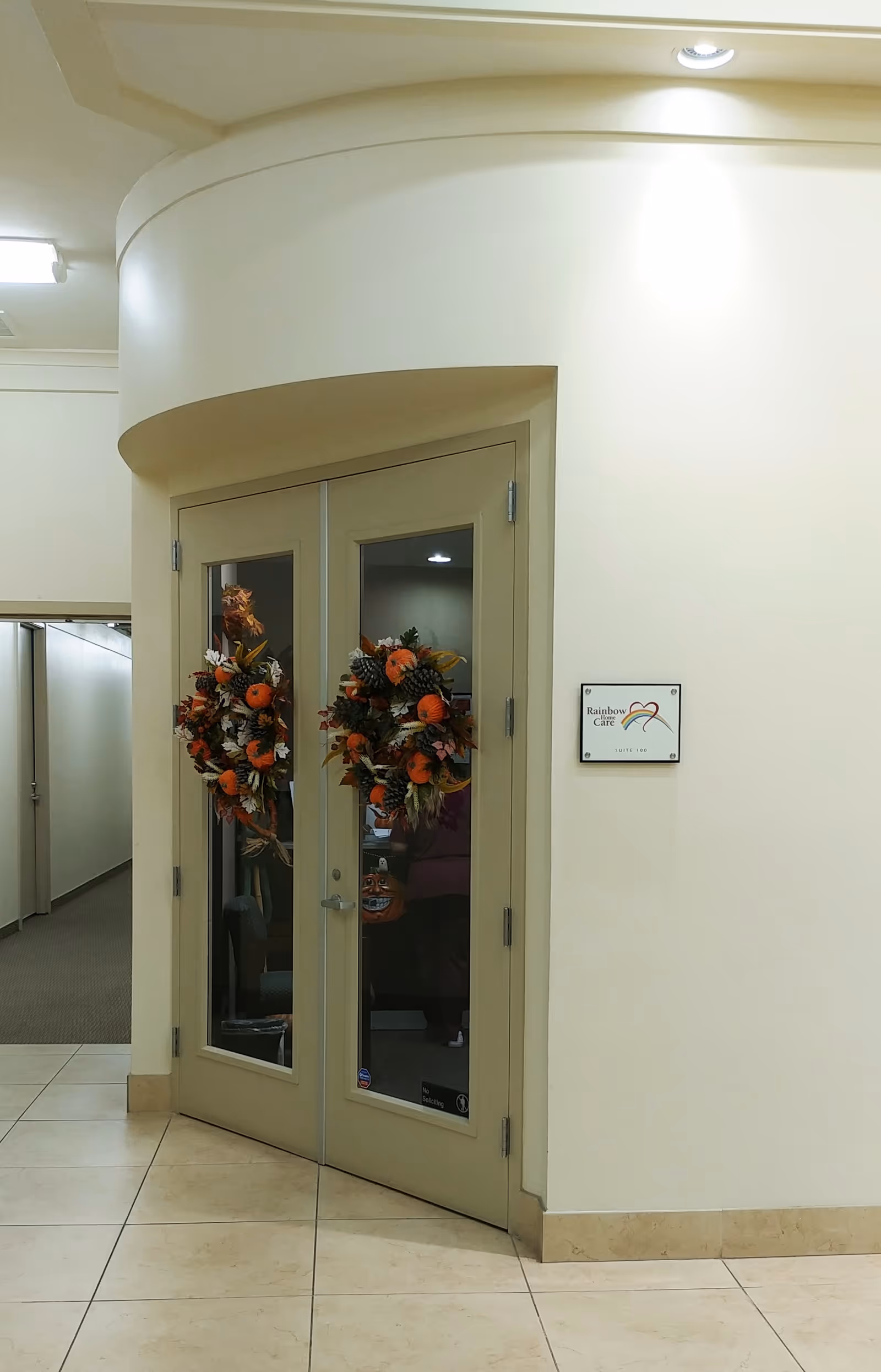 Double glass doors with autumn wreaths flank a hallway inside Rainbow Home Care Services.