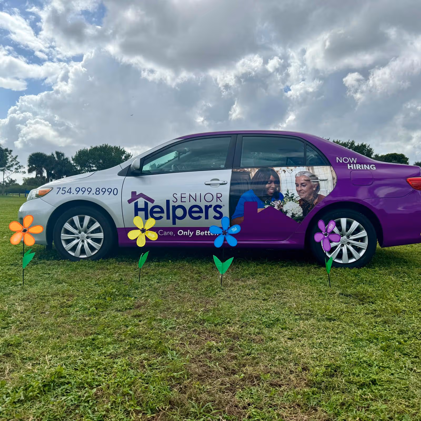 Purple and white Senior Helpers van on grassy field with colorful pinwheels