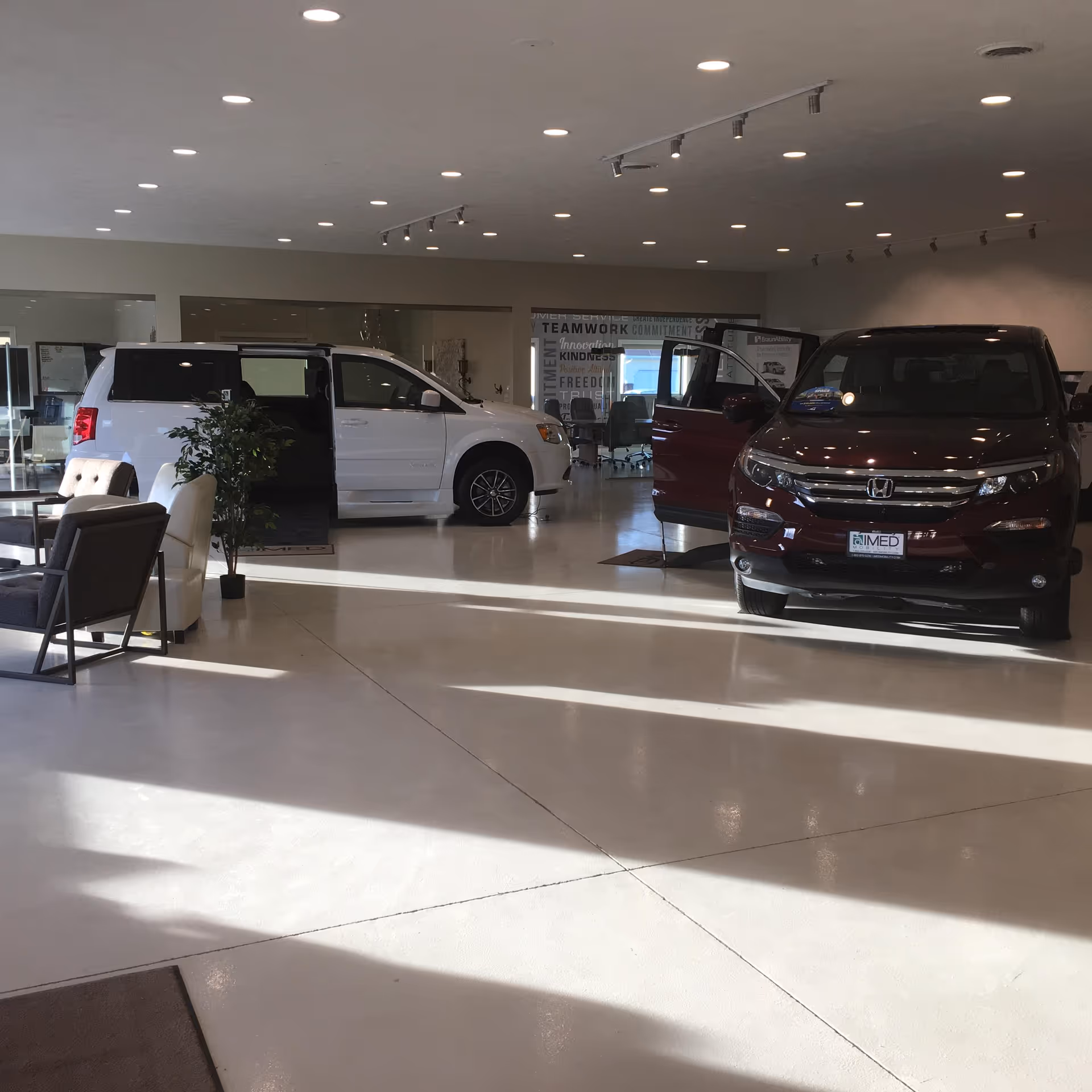 Interior of MobilityWorks showroom with white and red vans on display.