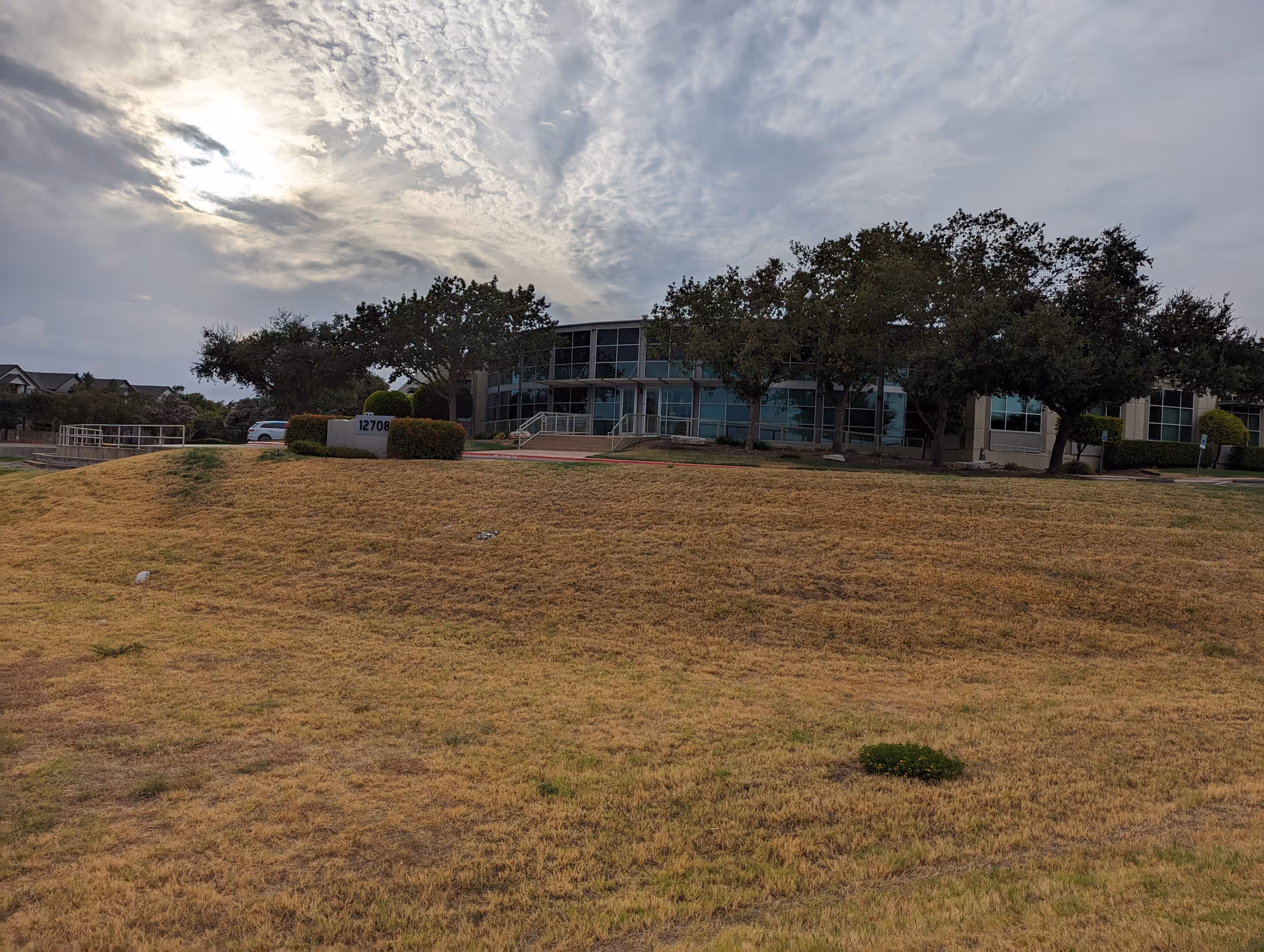 Exterior view of a senior living facility with a grassy foreground and trees.