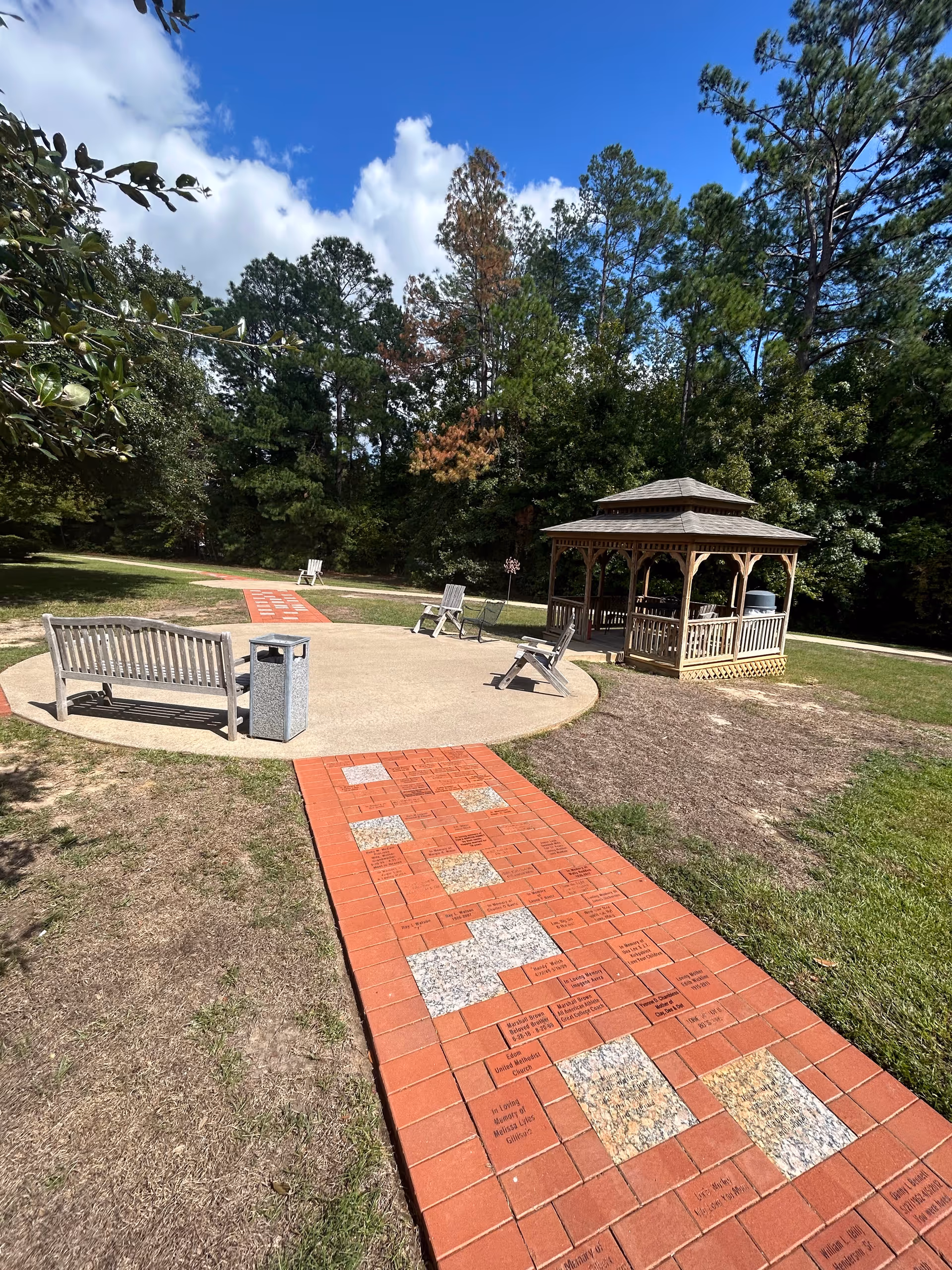 Outdoor courtyard at a hospice featuring a gazebo, benches, and engraved brick walkway.