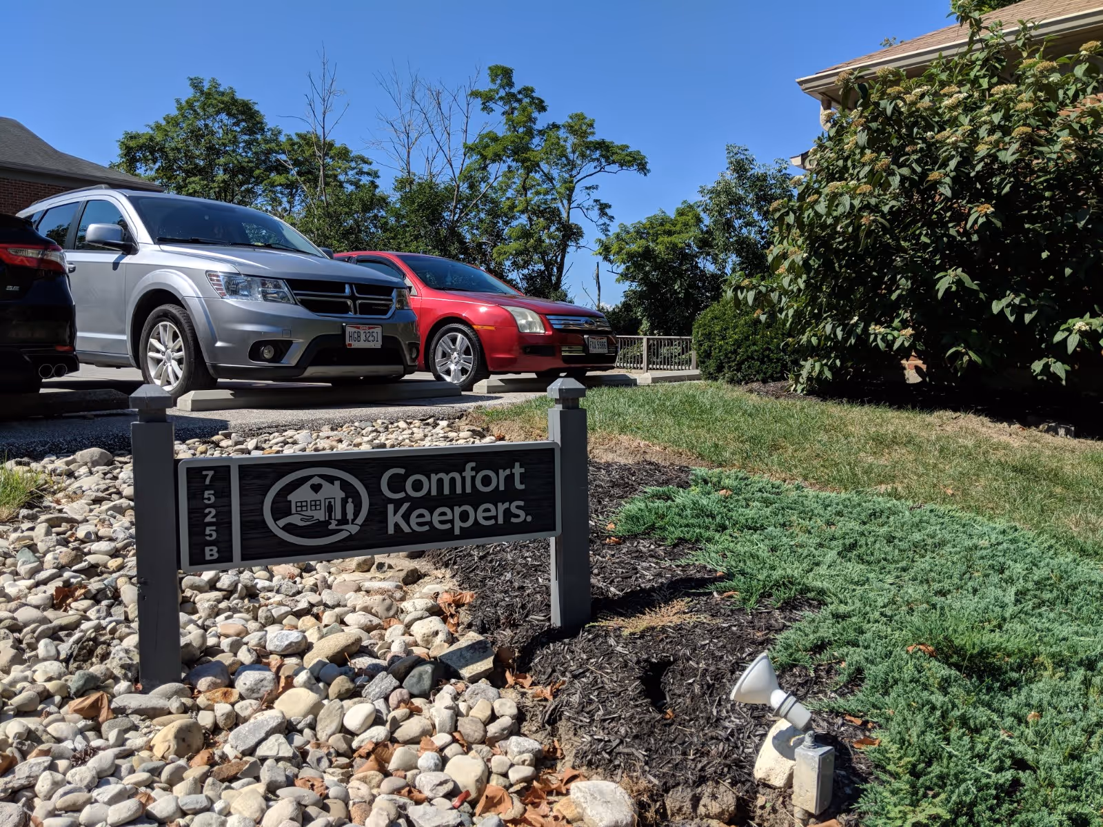 Outdoor view of Comfort Keepers facility with parked cars and a front sign.