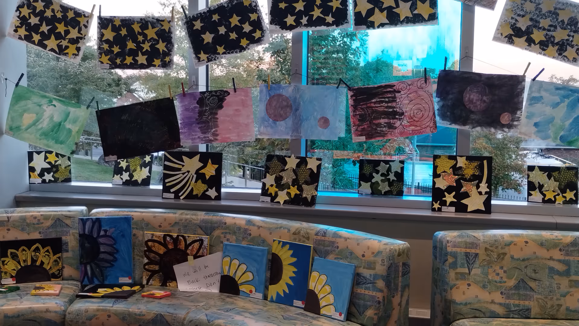 Colorful artwork hangs along windowed lounge with pastel-patterned seating.
