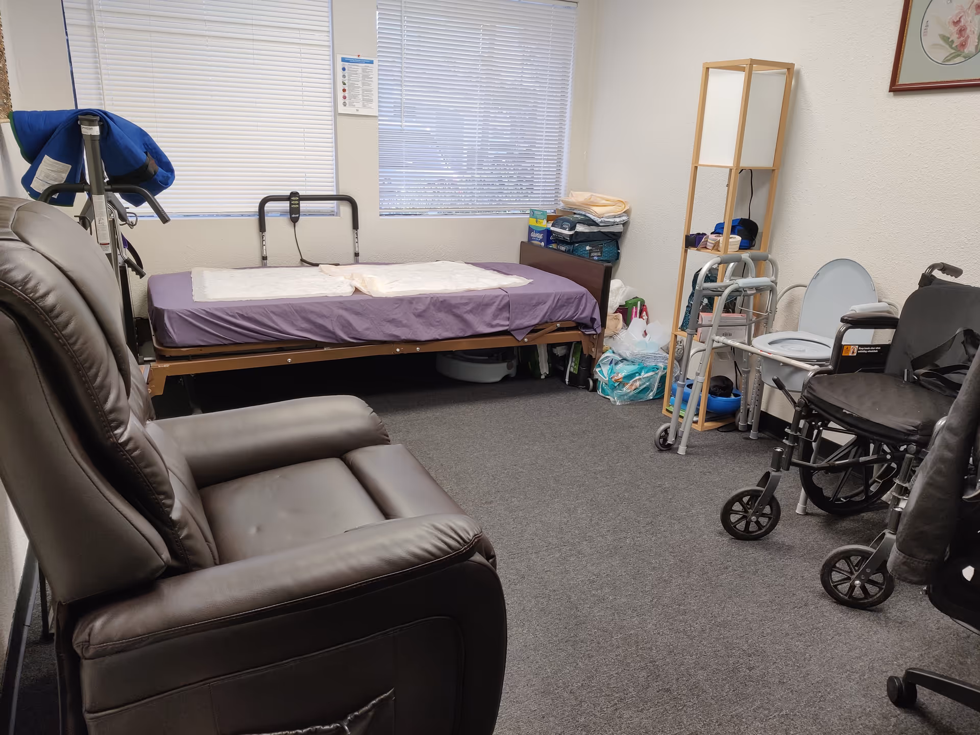 Interior room at Senior Helpers facility with bed, recliner, walker, wheelchair, and supplies.