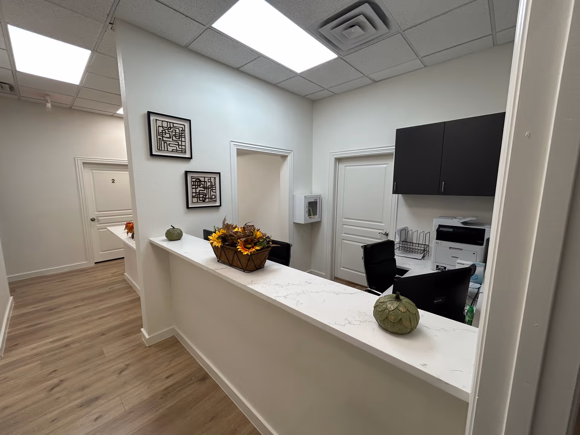 Reception desk area in Community First Primary Care, with white walls, wood flooring, and equipment.
