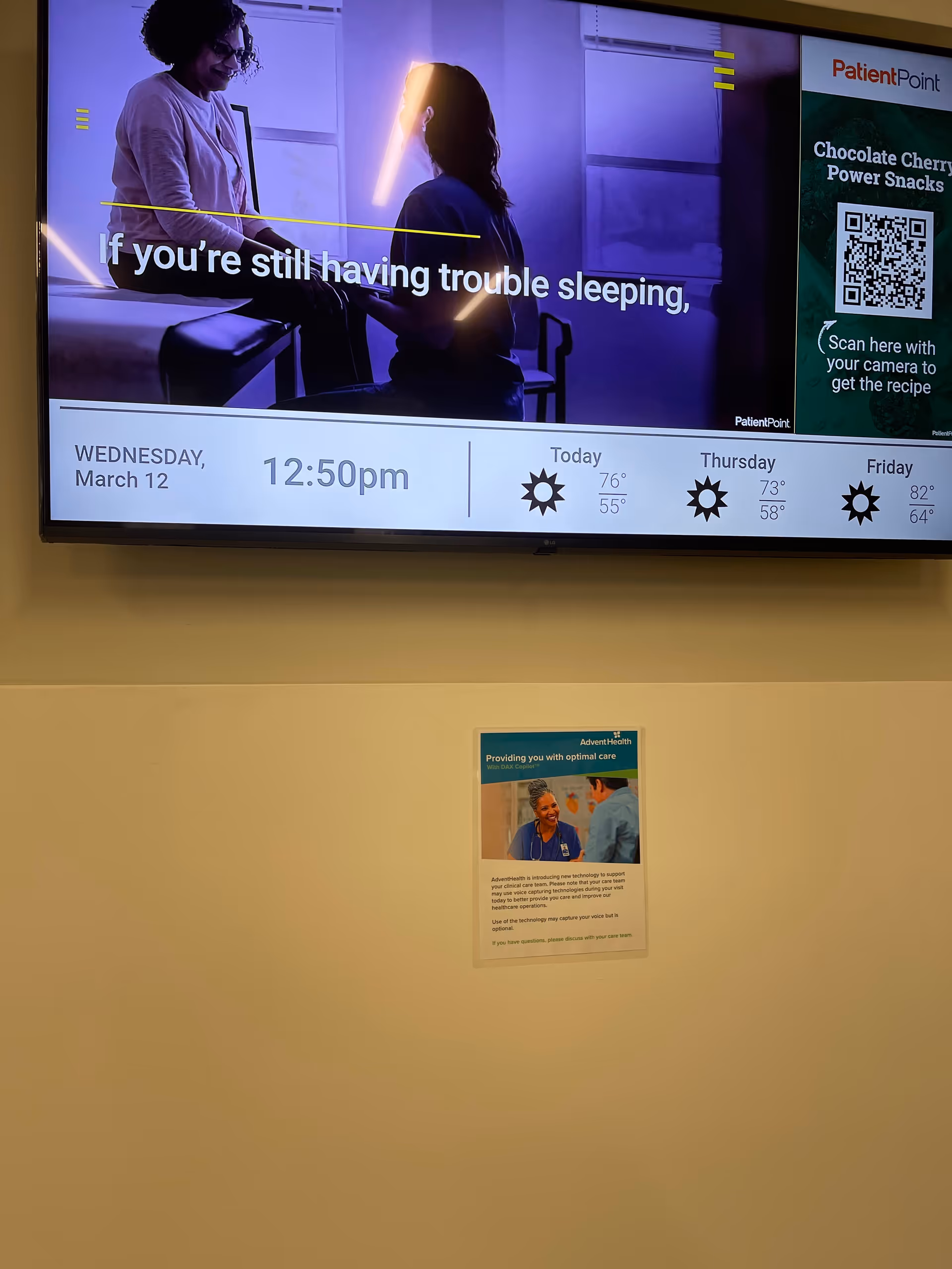 Large wall-mounted screen in a senior living lobby shows two people in a health ad.