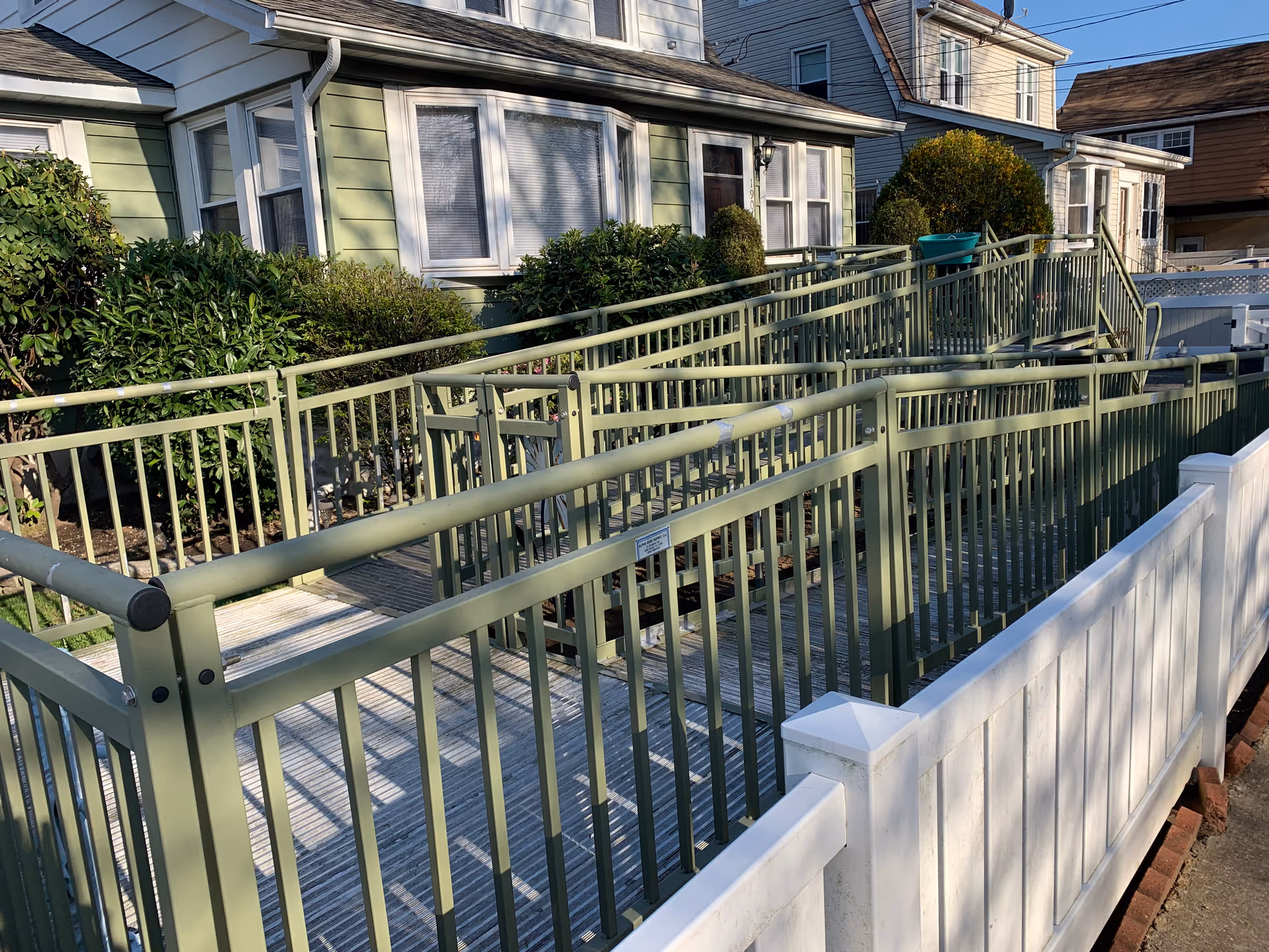 Exterior view of a long green ramp with rails beside a residential facility.