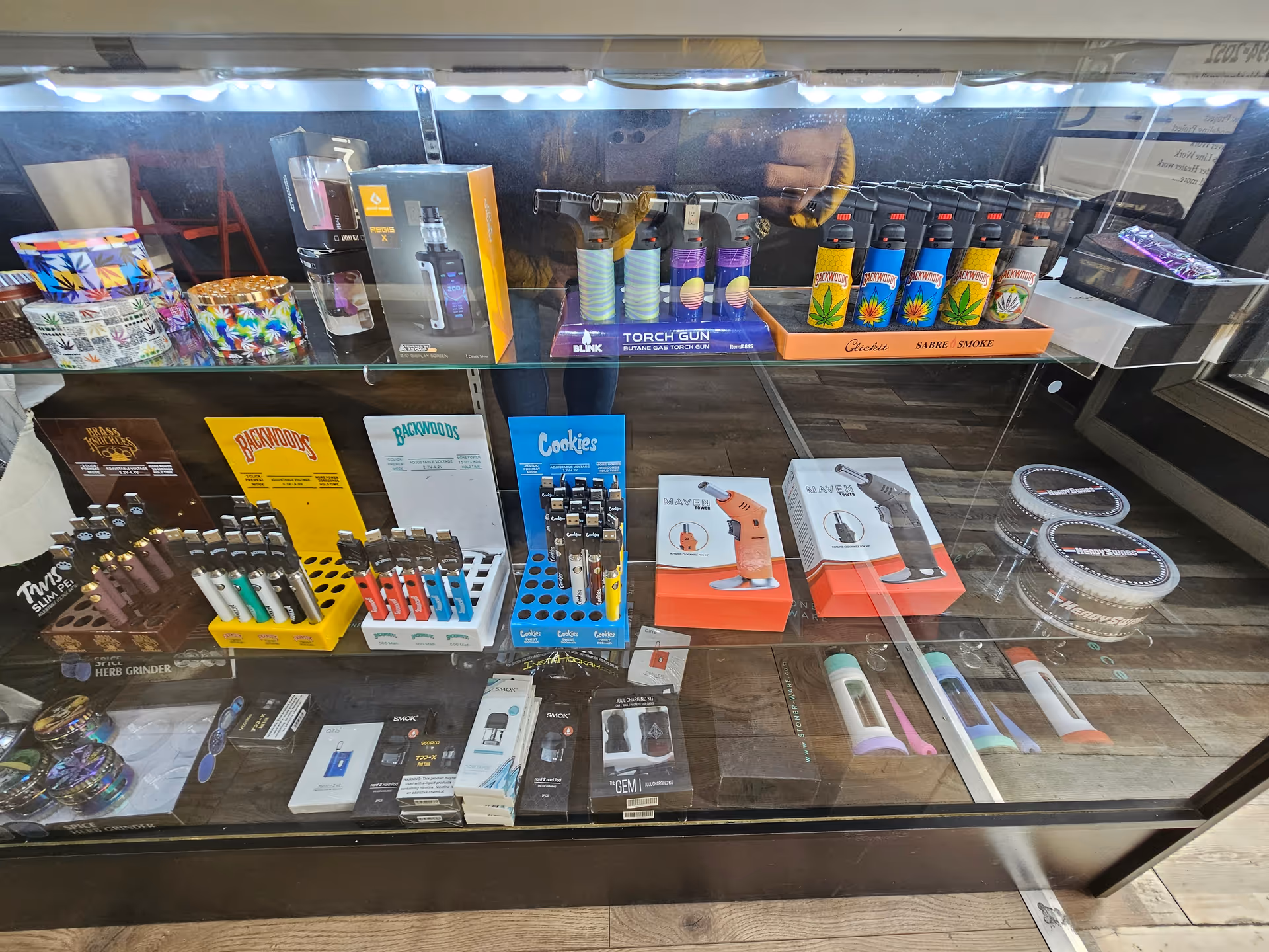 Glass display case with assorted smoking accessories and lighters.