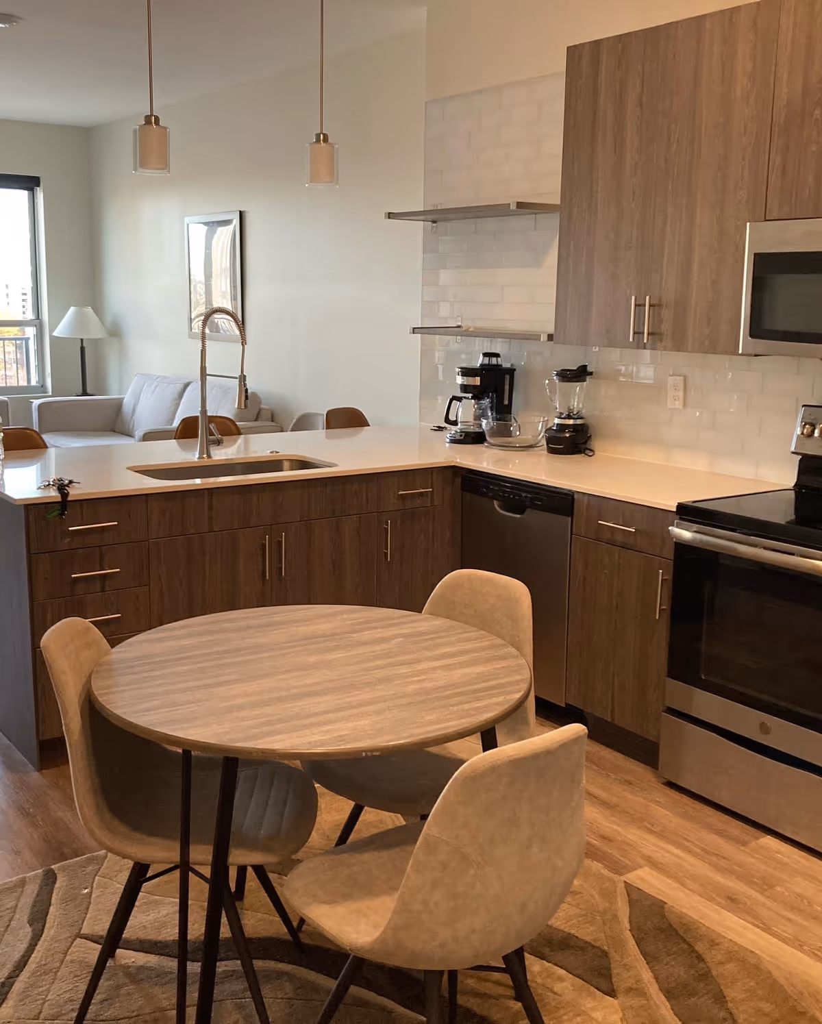 Open-concept kitchen with island, round dining table, and stainless appliances.