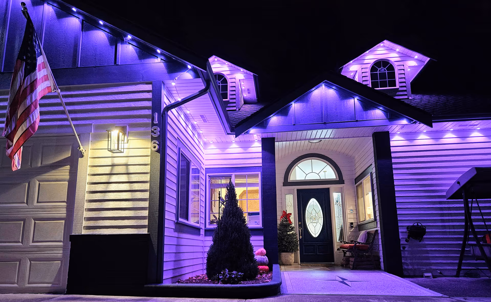Night exterior of a senior living facility's front entry, illuminated in purple with an American flag.
