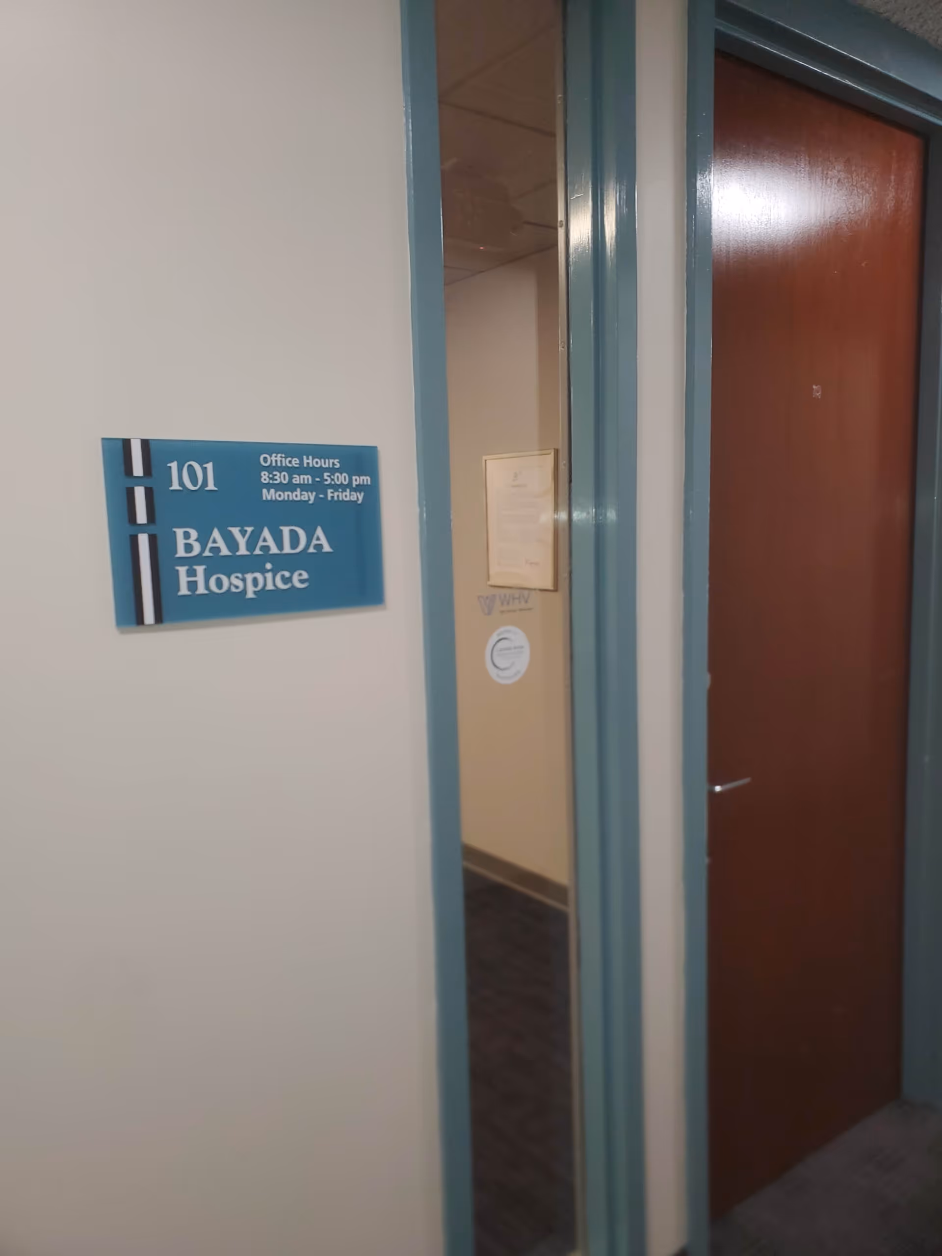 Hallway inside a BAYADA Hospice facility featuring a doorway and blue signage.