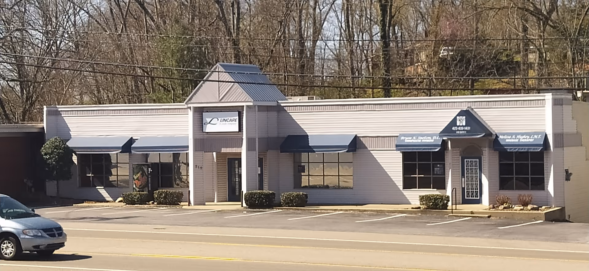 Front exterior of a LINCARE senior living building with awnings and parked car.