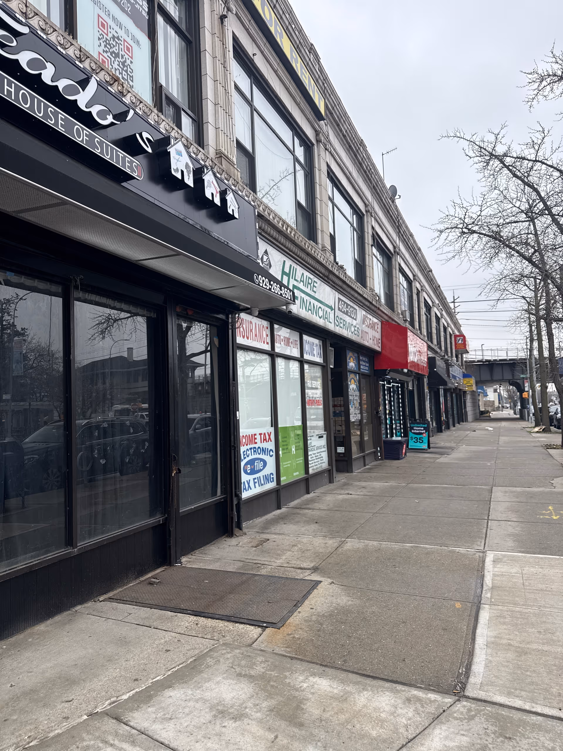 Street view of building fronts with shop signs along a sidewalk.