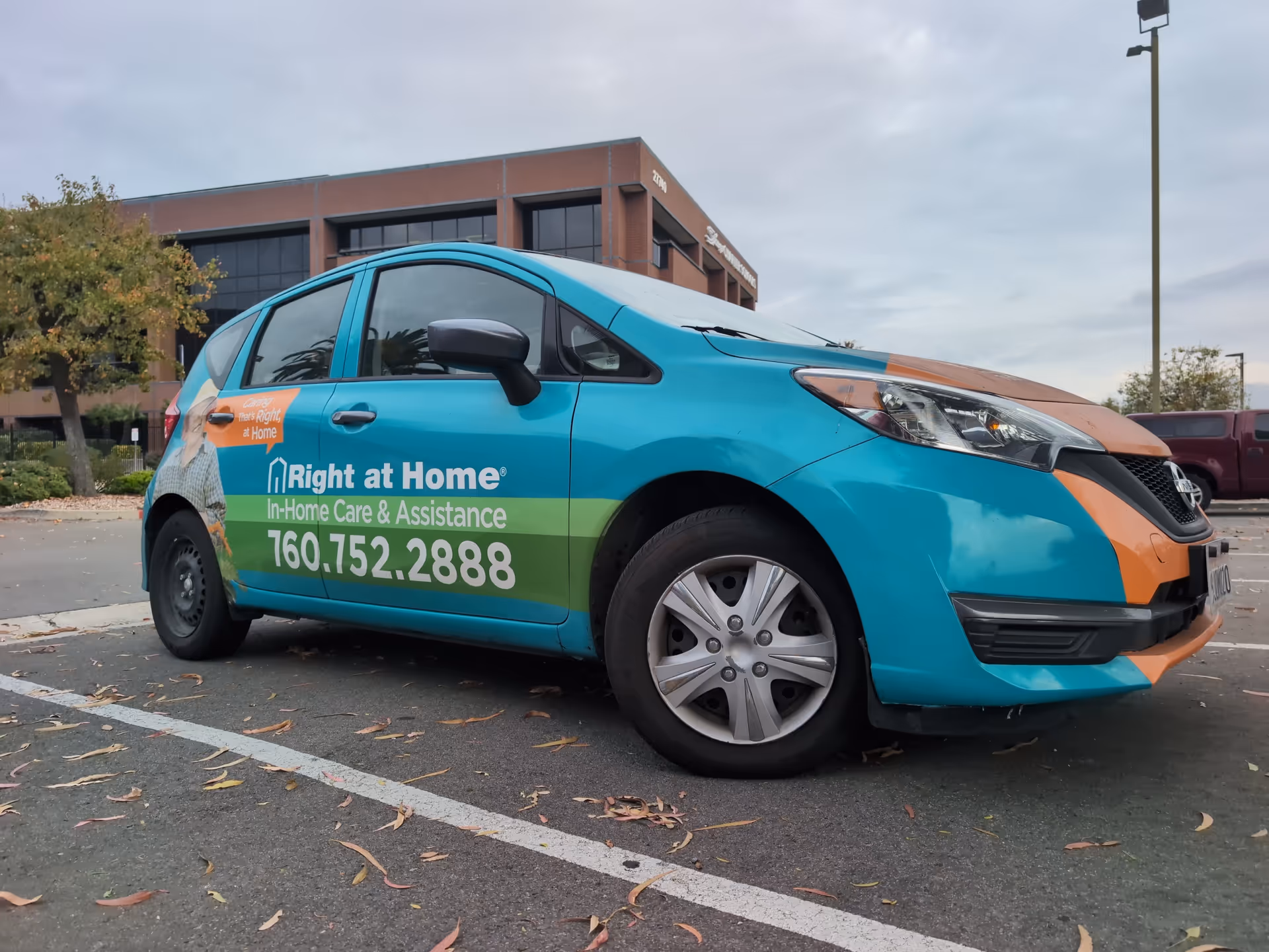 Colorful Right at Home van parked in a lot with a brick building behind.