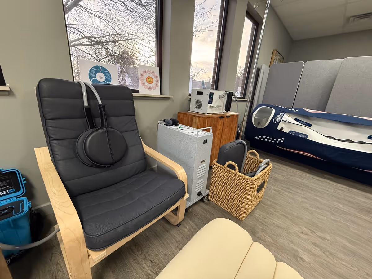 A treatment room with a padded chair, medical equipment, and a blue inflatable therapy bed.