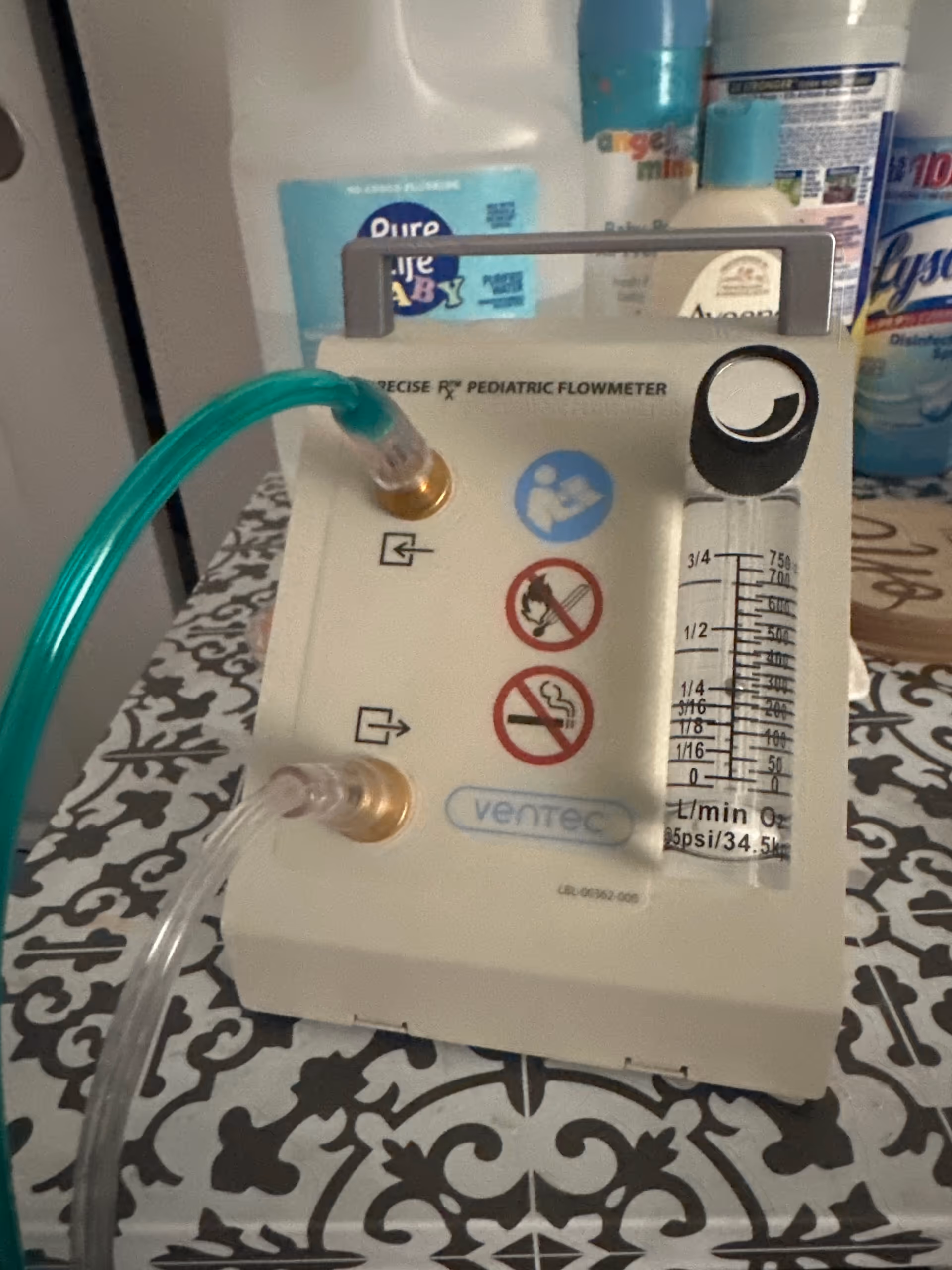 Close-up of a pediatric flowmeter with tubing on a patterned table.