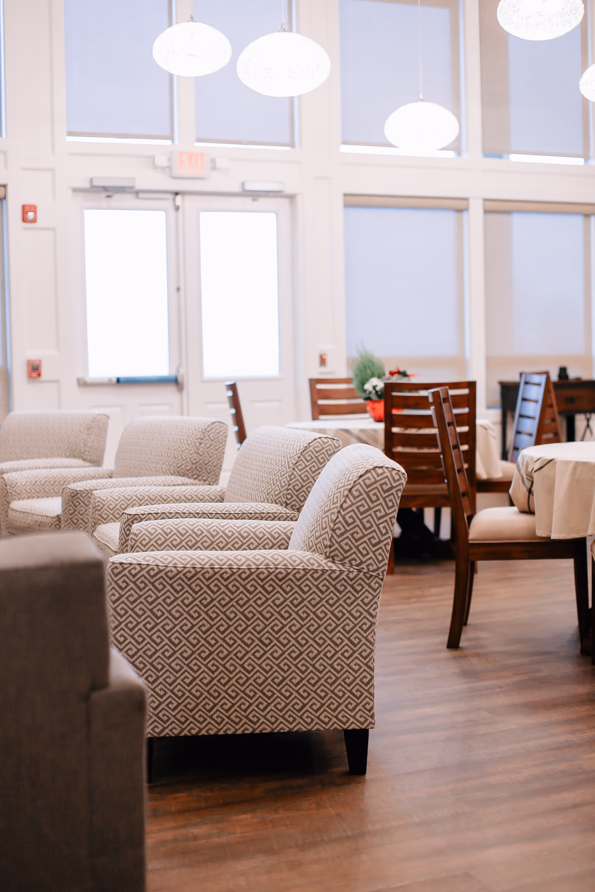 Bright dining area with patterned chairs, wooden tables, and large windows.