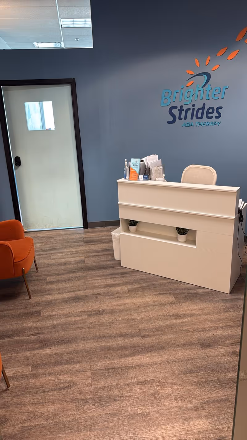 Reception area with white desk and Brighter Strides logo on blue wall
